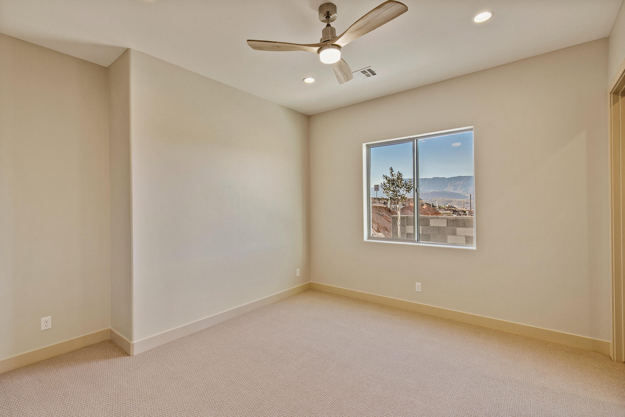 Carpeted room featuring a ceiling fan with integrated lighting, recessed ceiling lights, a large window, and beige wall paint