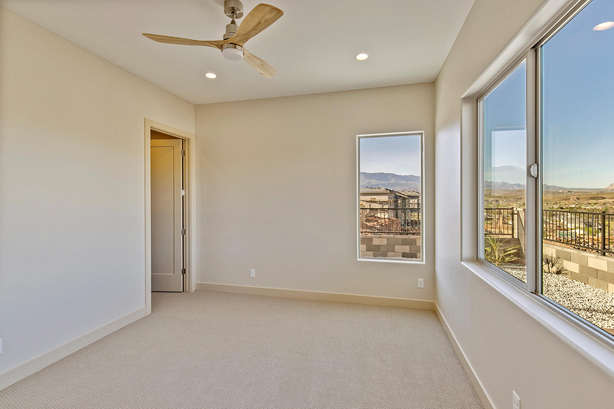 Carpeted room featuring a ceiling fan, recessed lighting, and multiple windows