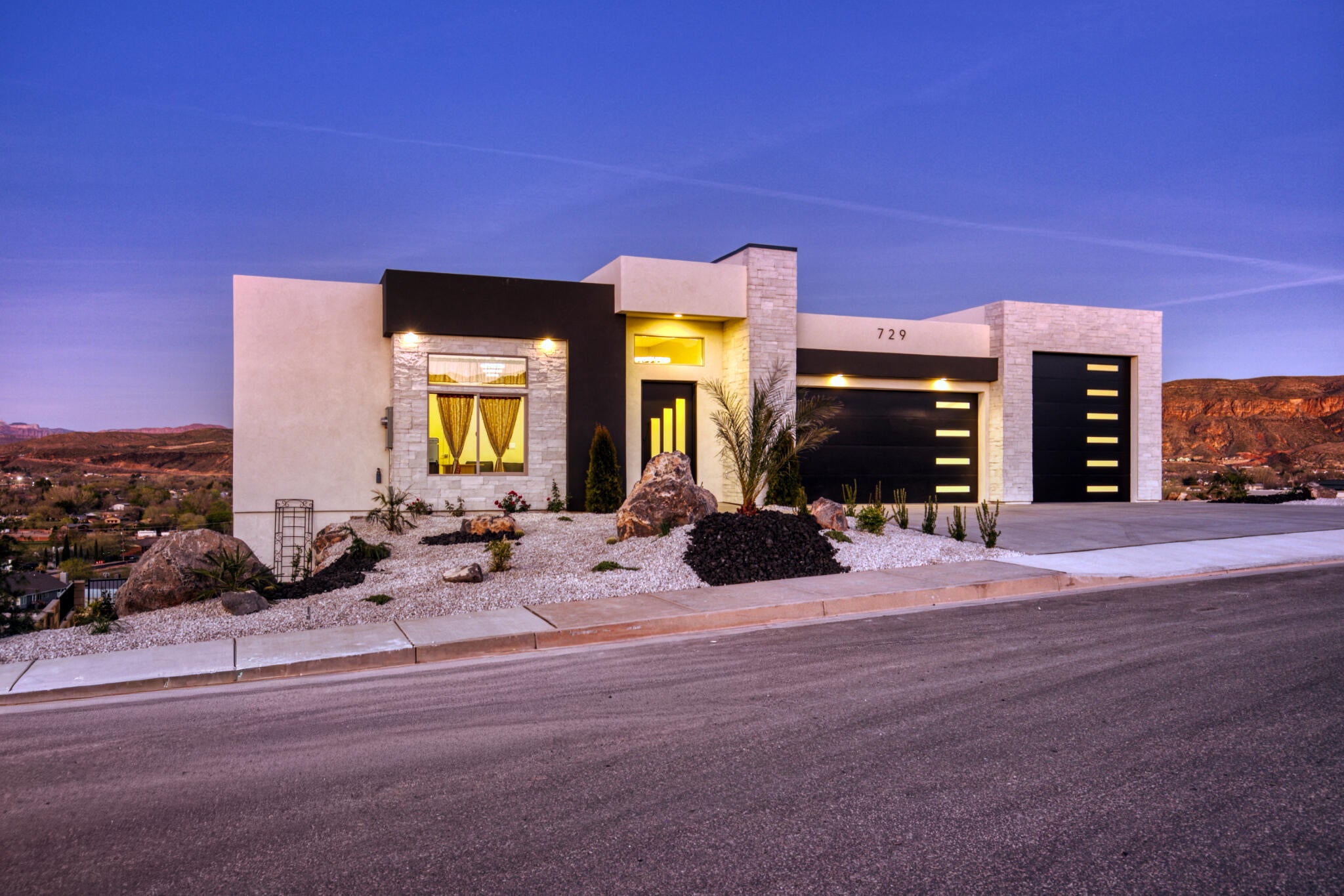 Modern architectural exterior featuring stone veneer accents, smooth stucco finishes, and dark horizontal siding