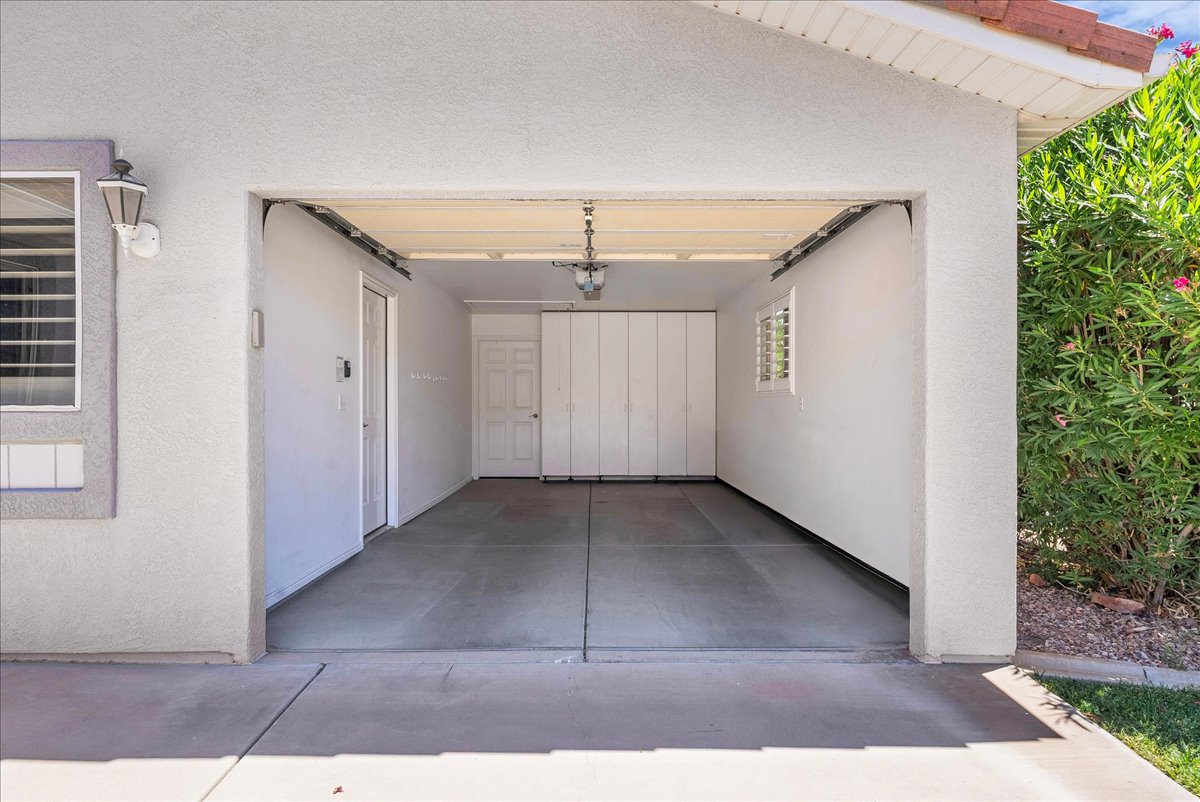 Two-car garage with concrete flooring, interior access door, accordion-style storage doors, and a window with horizontal blinds