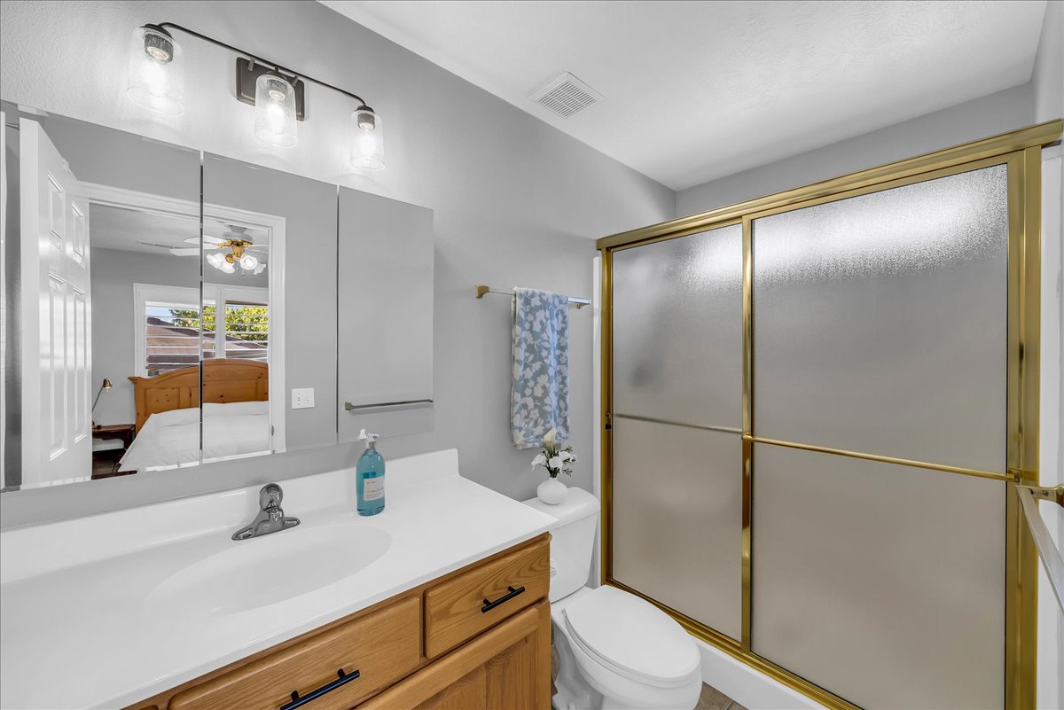 Bathroom featuring a single vanity with a white countertop, wood-finish cabinetry, and a mirrored medicine cabinet