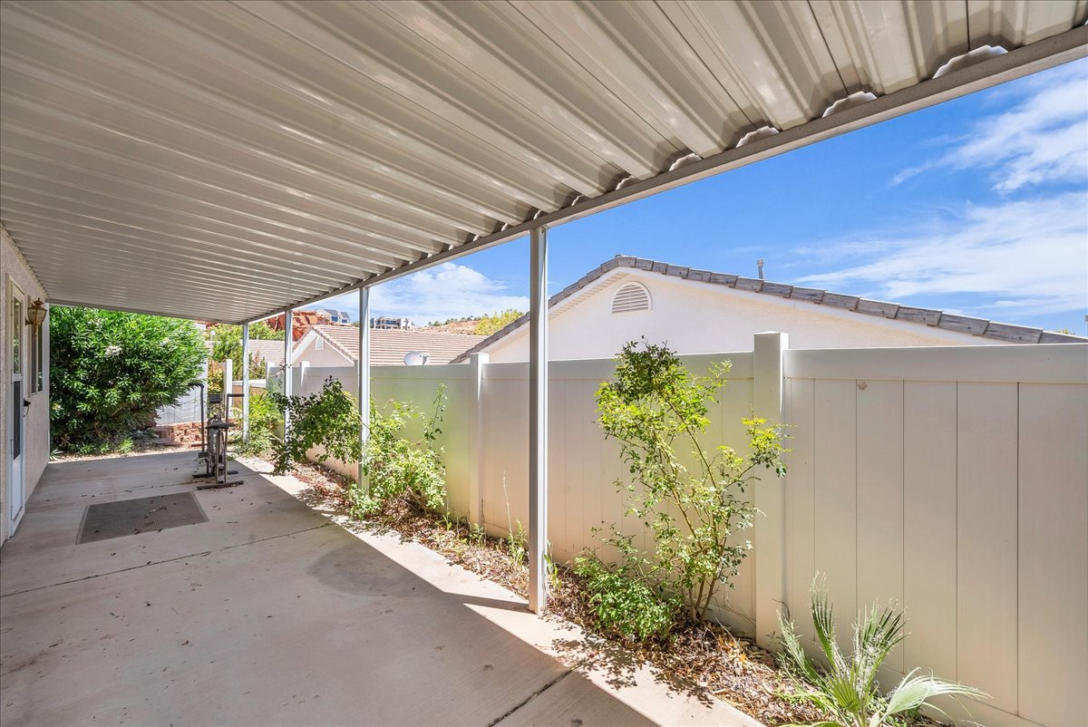 Covered patio featuring a corrugated metal roof, concrete flooring, and an integrated garden bed