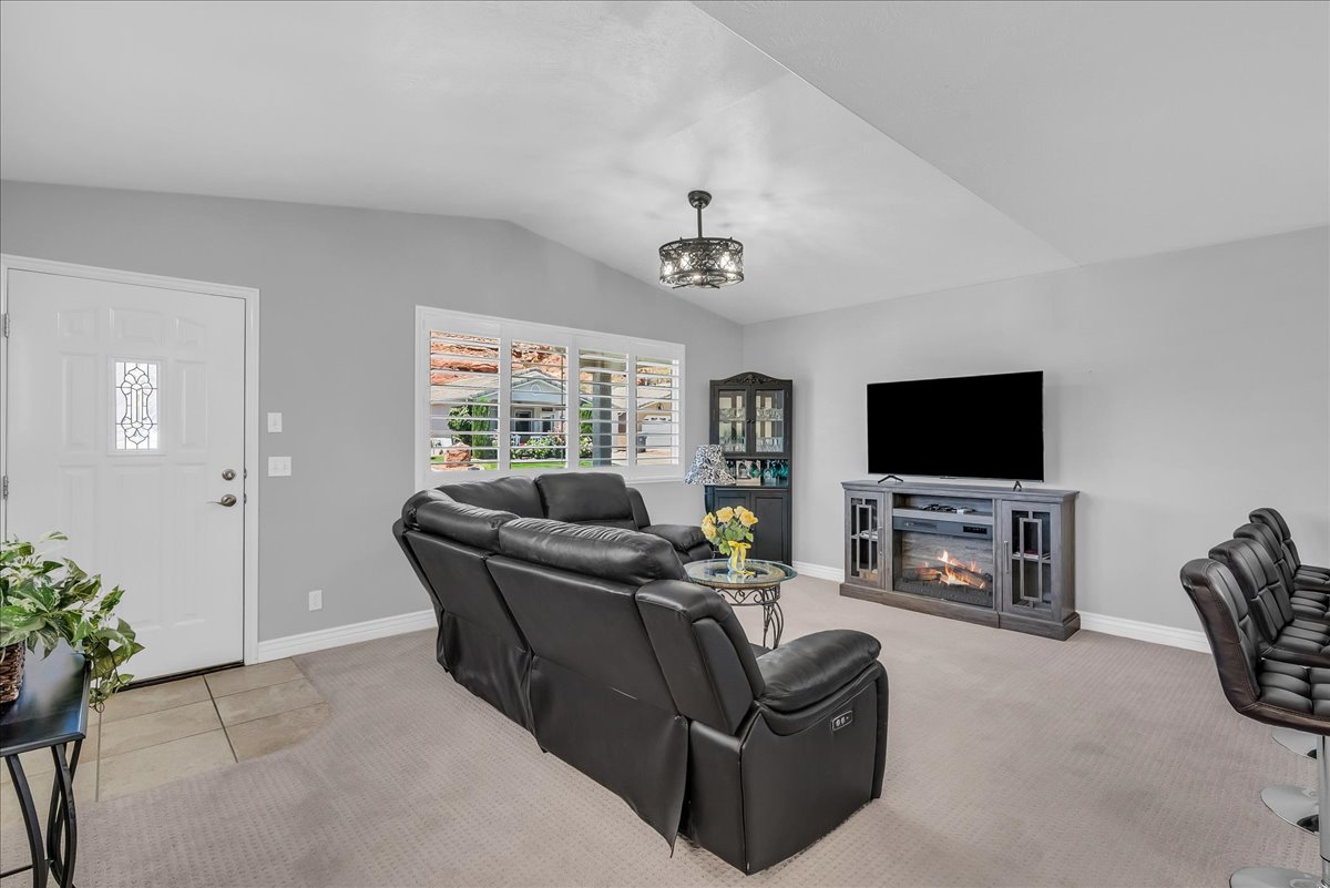 Living area featuring vaulted ceilings, a decorative lighting fixture, and a built-in electric fireplace media console