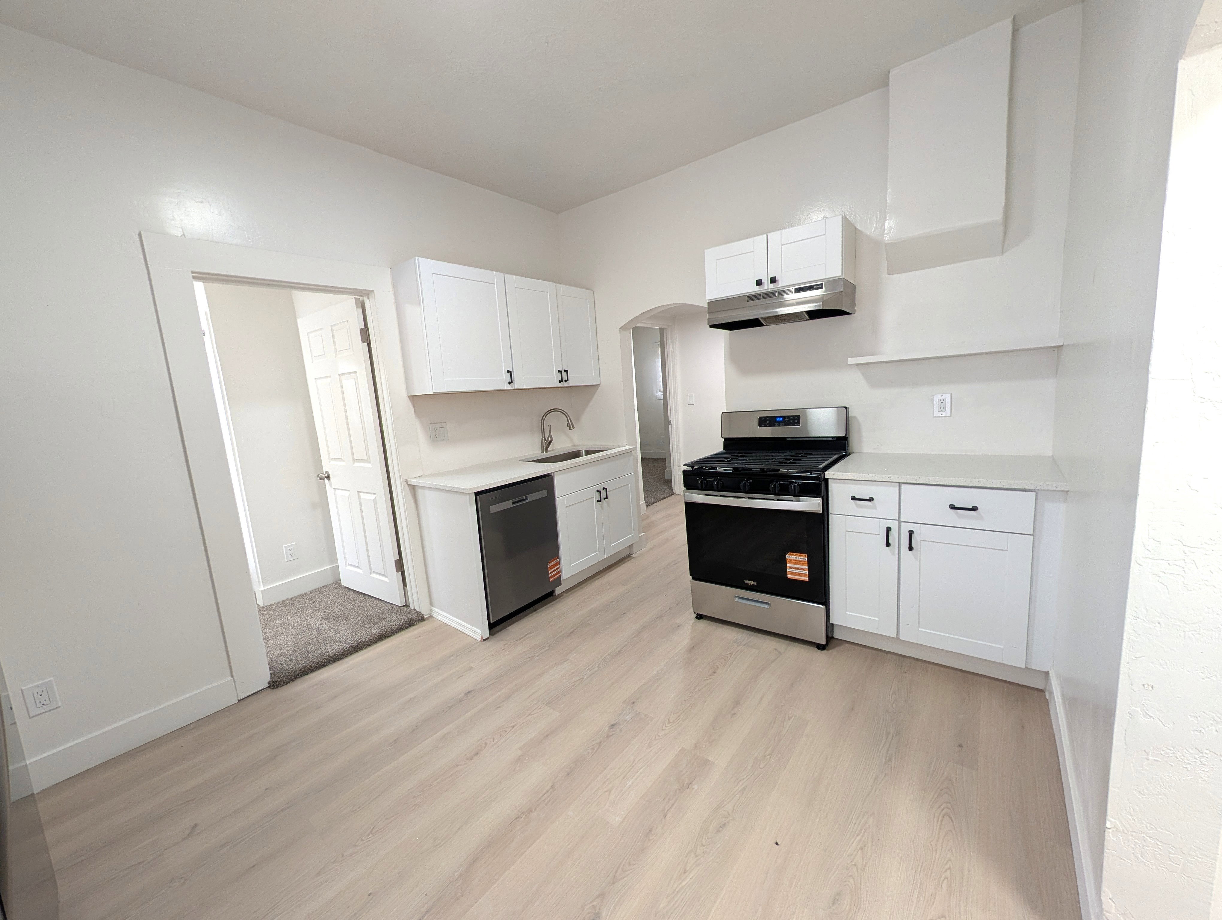 Kitchen featuring light wood-finish flooring, white cabinetry with matte black hardware, stainless steel appliances, and light-colored countertops