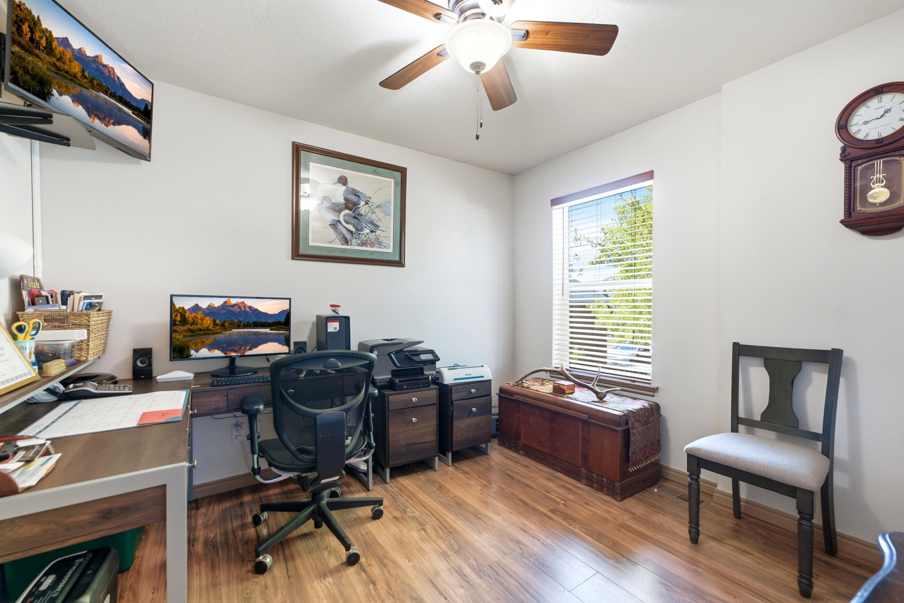 Bedroom currently used as an office . Interior room with wood-finish flooring and a ceiling fan