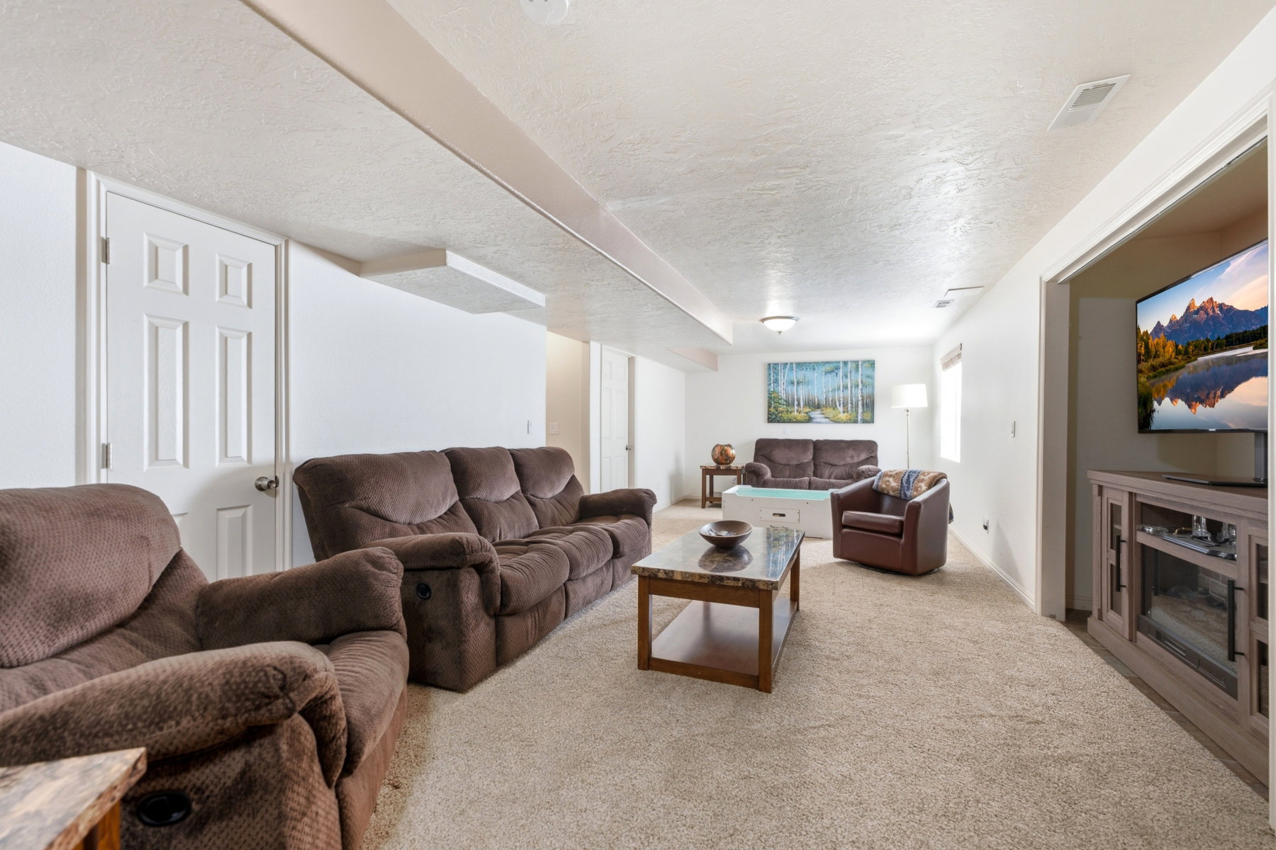 Spacious lower-level area with neutral carpeting, white walls, and recessed lighting