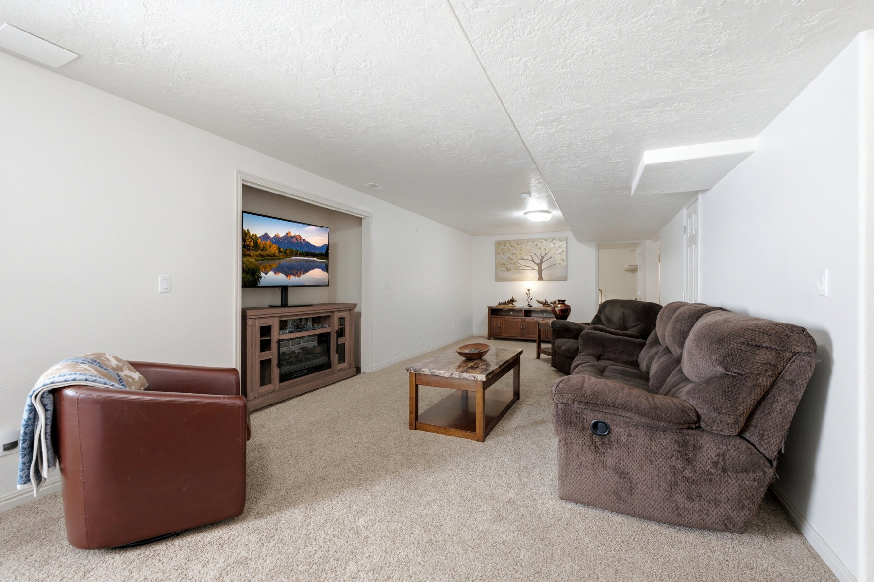 Carpeted living area featuring white walls and a textured ceiling