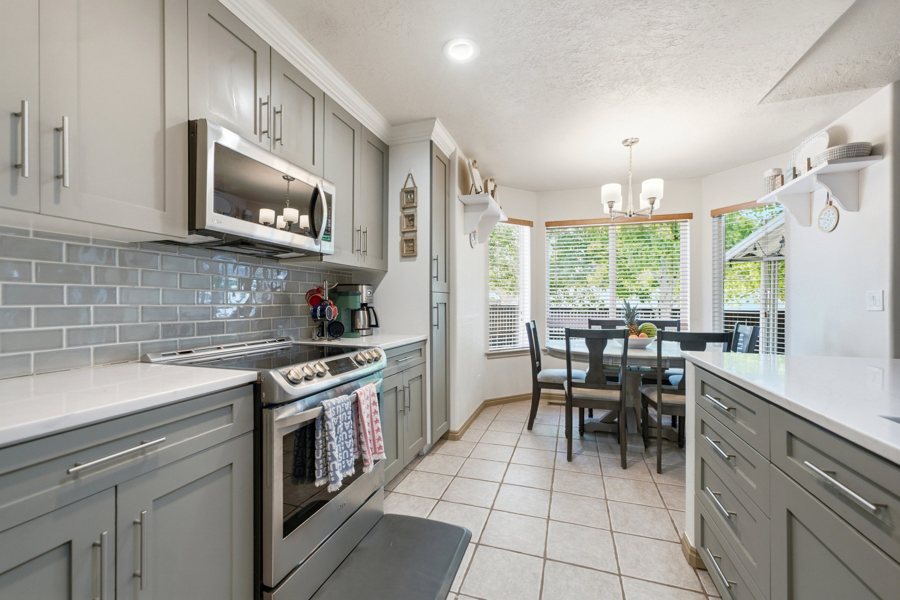 Contemporary kitchen featuring gray shaker cabinetry, stainless steel appliances, a subway tile backsplash, and light-tone countertops