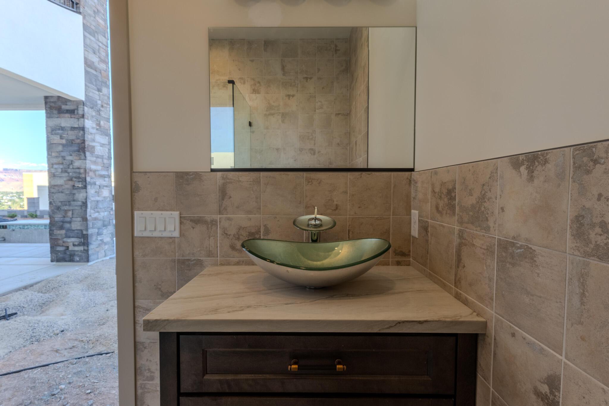 Bathroom vanity featuring a vessel sink, single-handle faucet, stone countertop, and dark wood cabinetry
