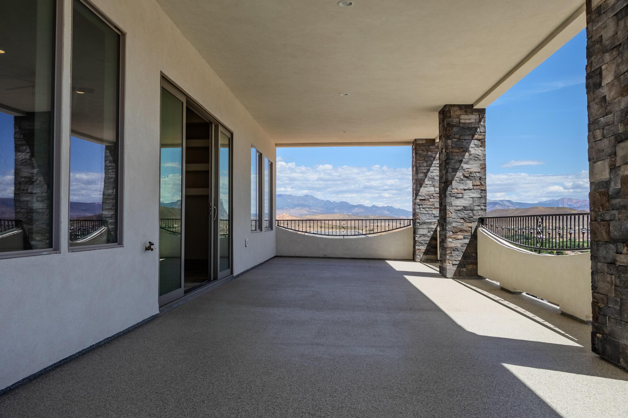 Expansive covered patio with a textured concrete surface and stone-clad architectural pillars