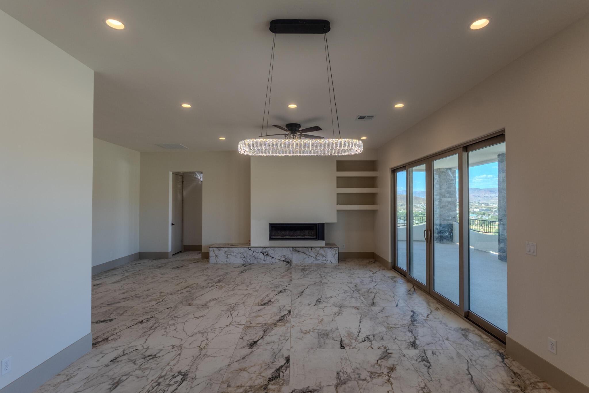 Spacious room featuring marble-look flooring, a linear electric fireplace with a marble-look hearth, built-in shelving, and recessed lighting