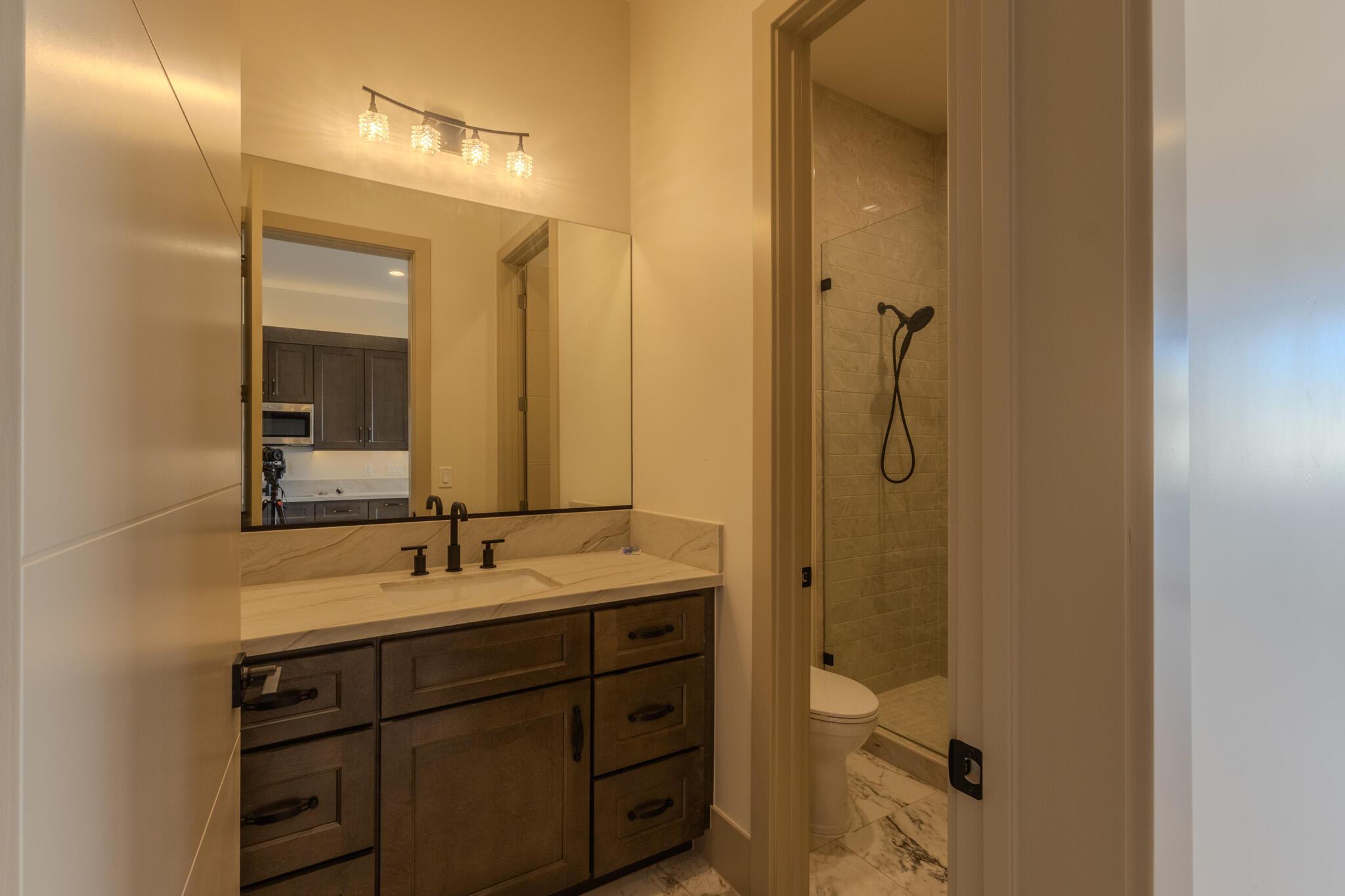 Bathroom featuring a wood-finish vanity with a single basin, light-toned countertop, and dark-finish hardware