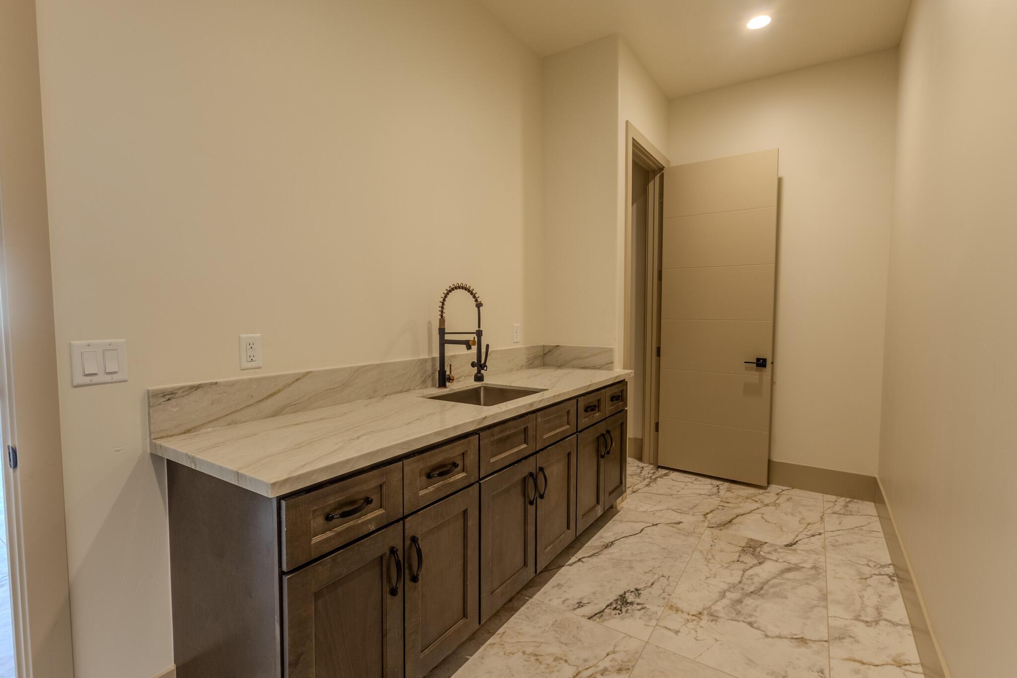 Custom cabinetry with dark hardware and a built-in sink under a stone-finish countertop