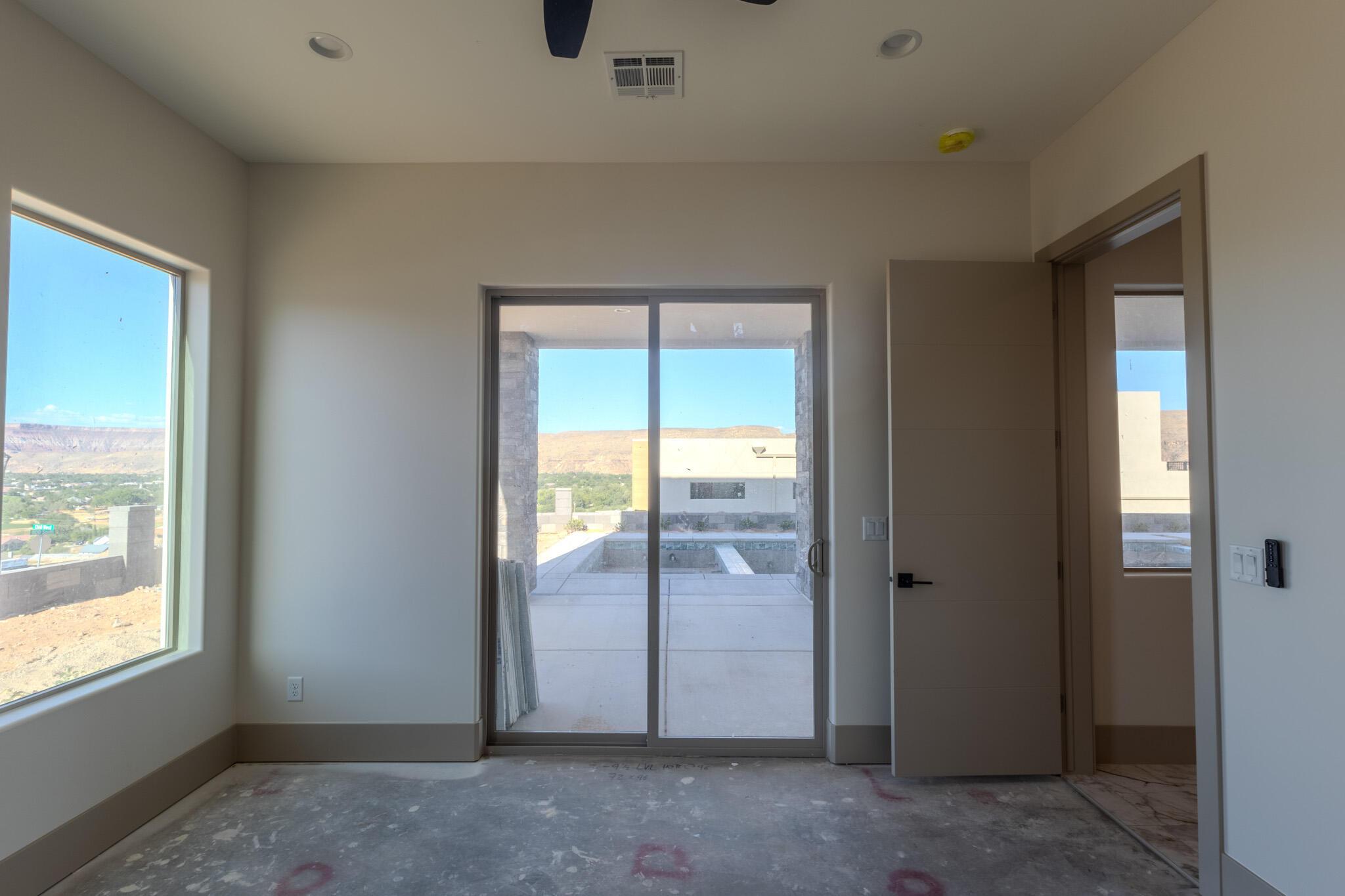 Sliding glass door opening to an outdoor patio with a surrounding desert landscape