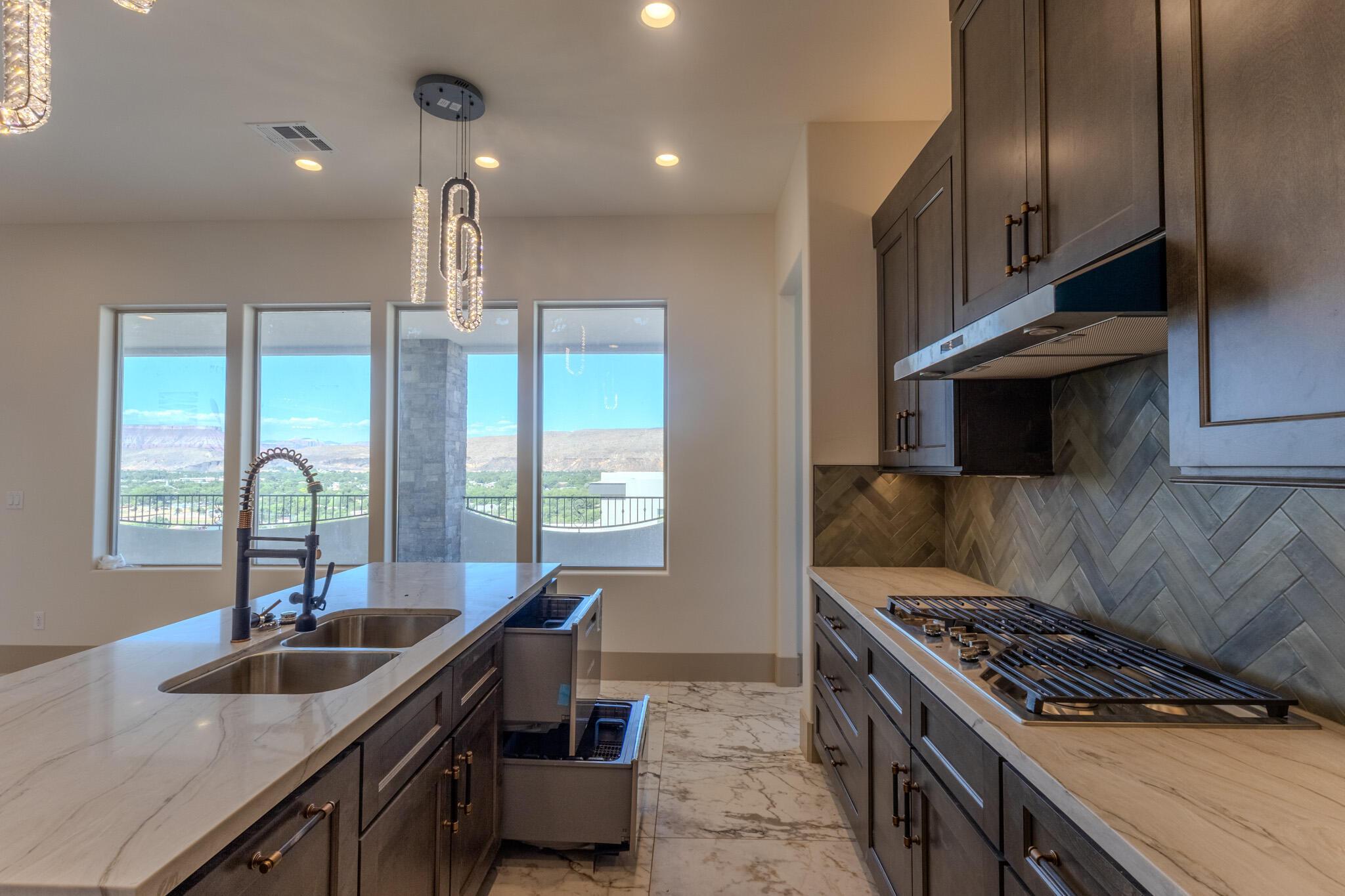Modern kitchen with a dual-basin stainless steel sink, black gooseneck faucet, and integrated trash/recycling bins