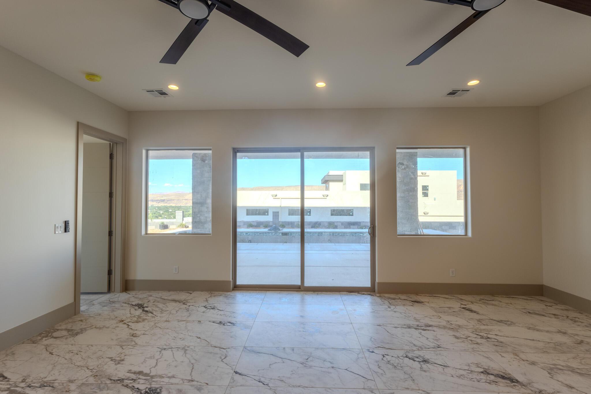 Expansive room featuring marble-look flooring, multiple windows, and a sliding glass door