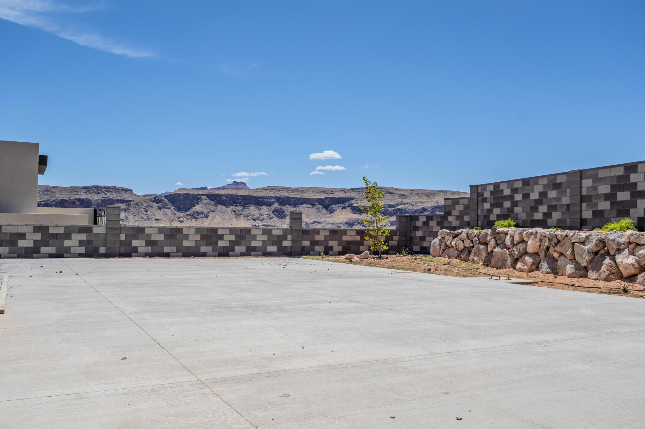 Expansive concrete pad bordered by a decorative block wall and a natural stone retaining wall