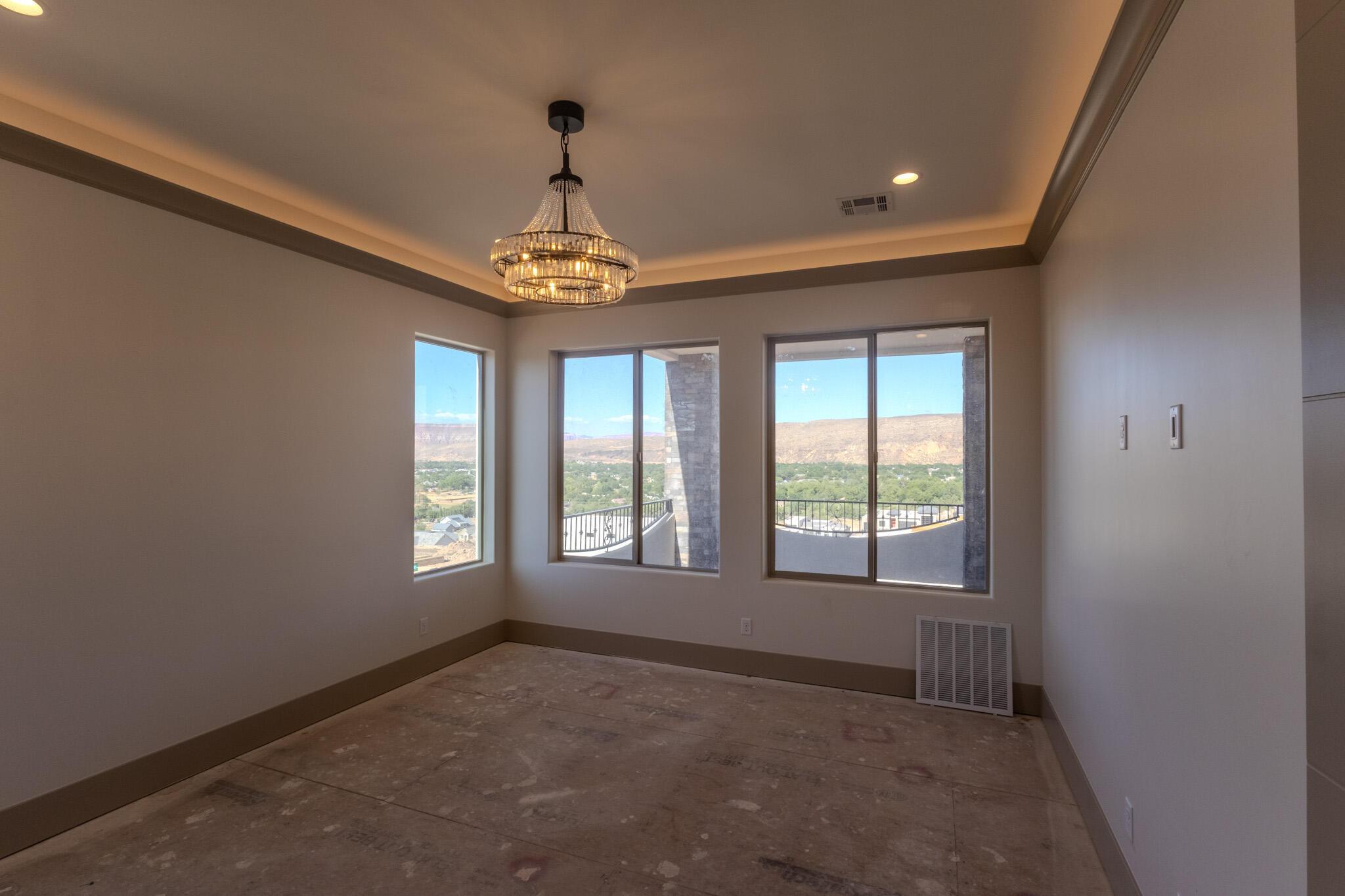 Room featuring multiple windows, a tiered crystal chandelier, tray ceiling with cove lighting, and crown molding