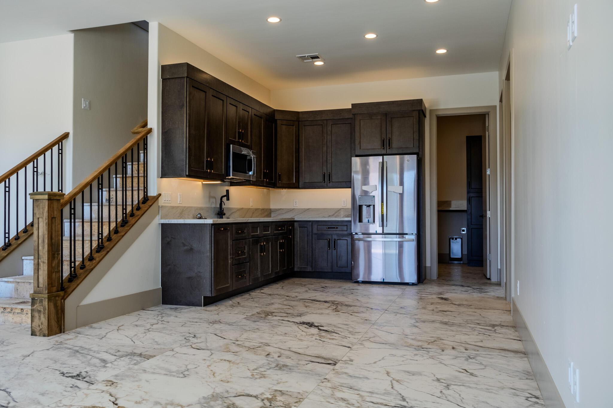 Corner wet bar with dark wood cabinetry, integrated microwave, and stainless steel refrigerator