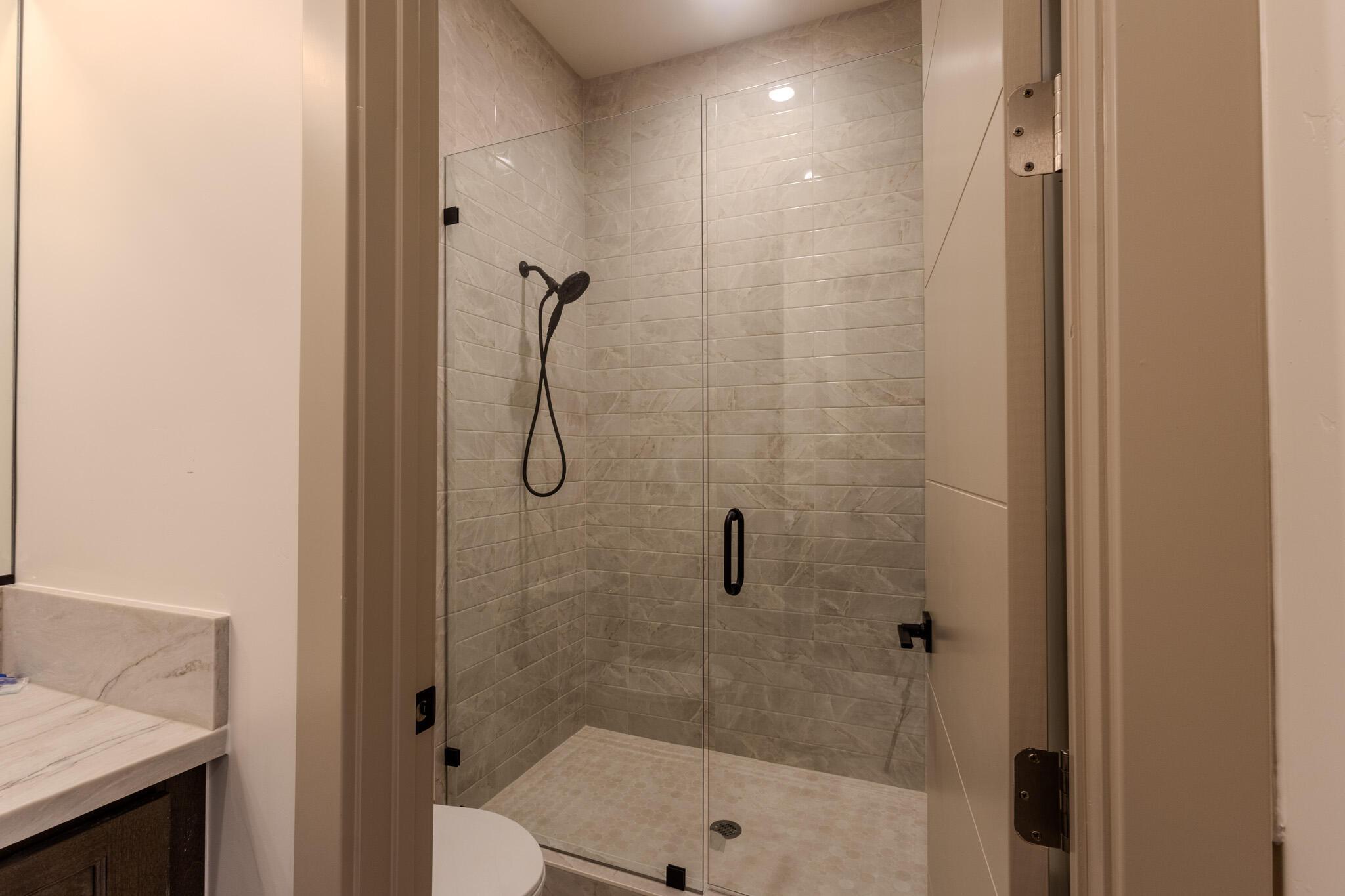 Glass-enclosed shower with subway-style tile surround and matching tile floor
