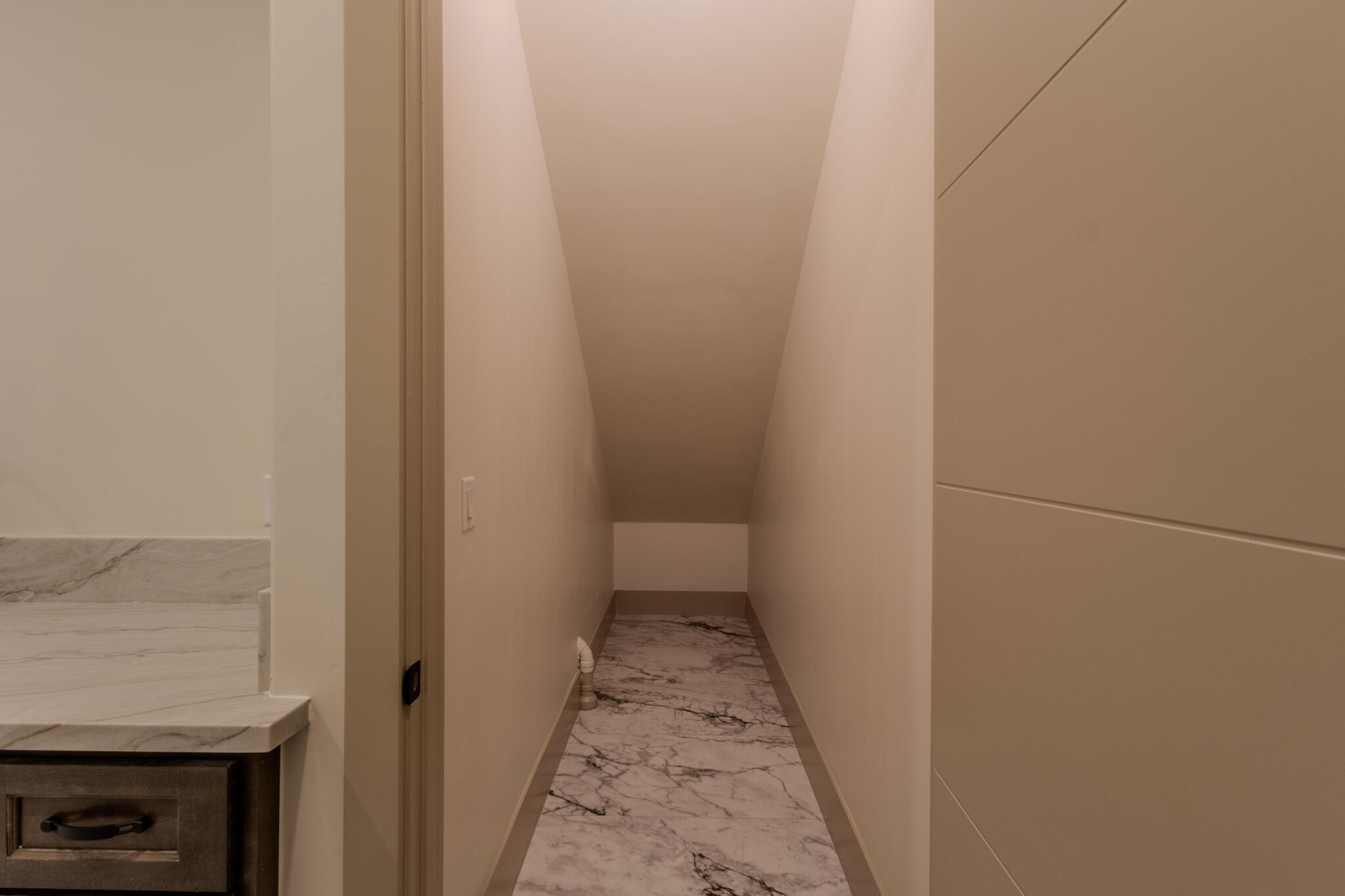 Finished attic storage space featuring sloped ceilings, light-toned wall paint, and marble-look flooring
