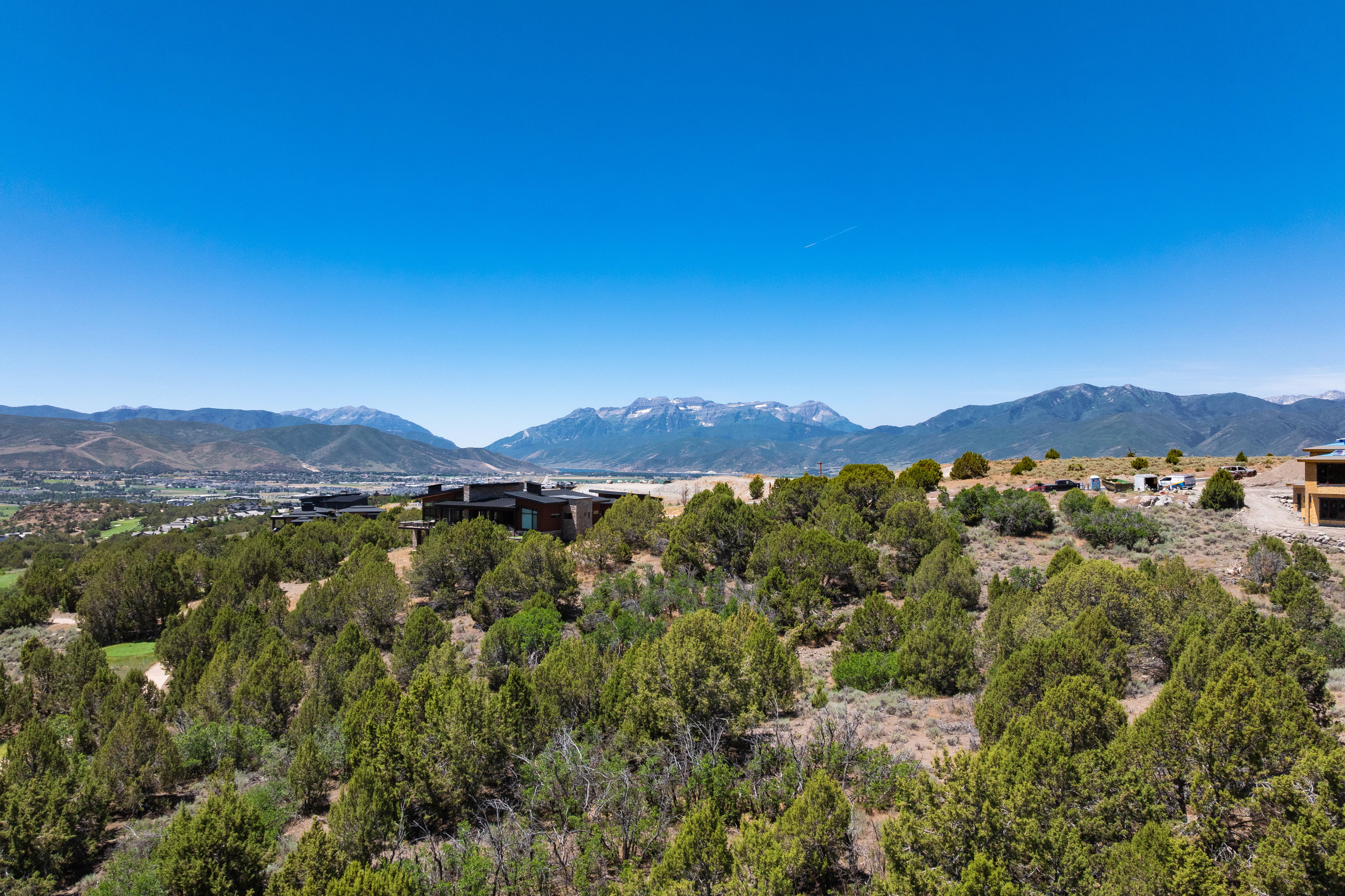 Expansive property featuring a mountainous backdrop, scattered evergreen trees, and modern architectural structures