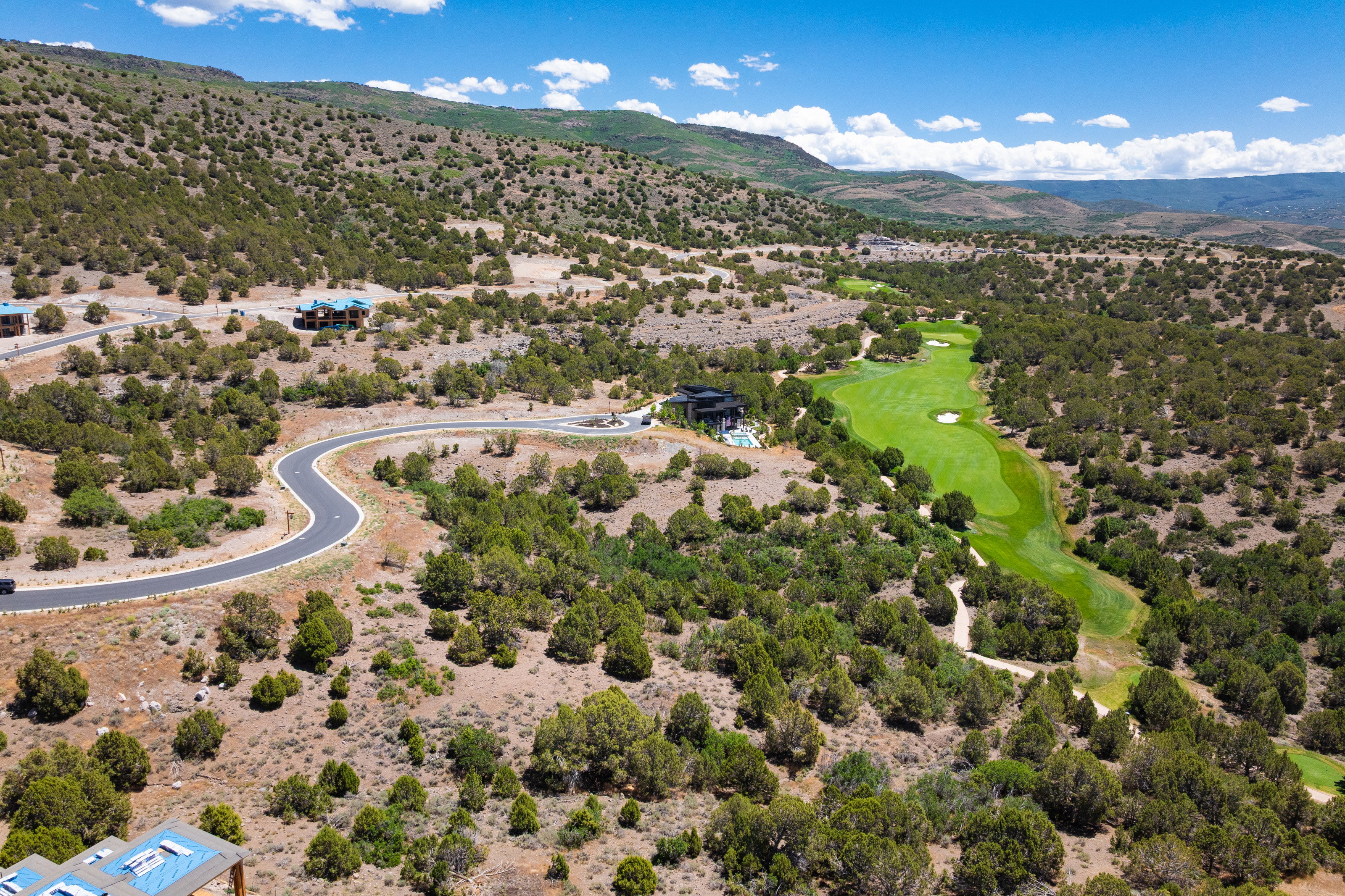 Aerial perspective showcasing a golf course fairway, surrounding natural landscape, and residential properties