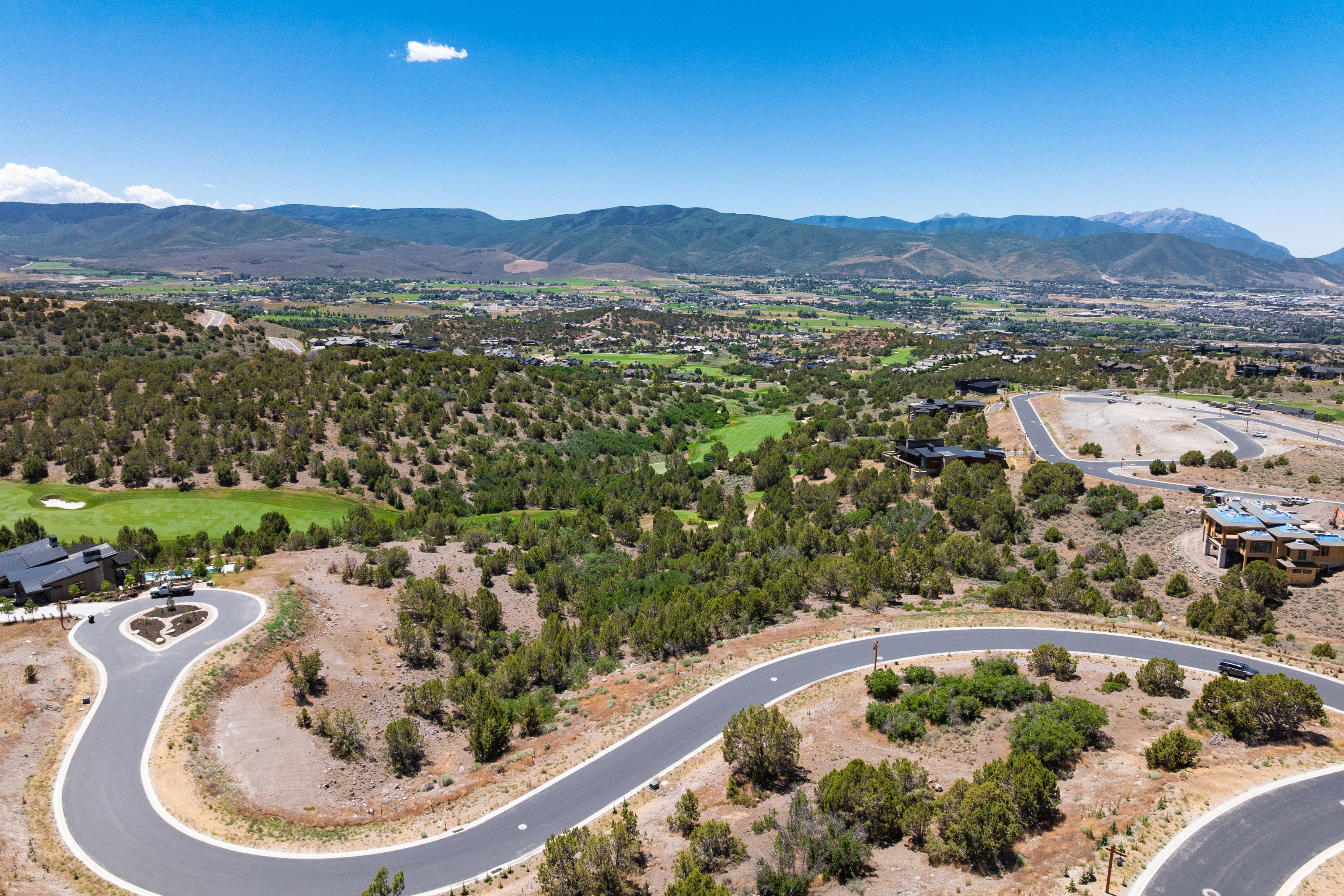 Expansive landscape featuring developed roadways and scattered residences within a natural, tree-filled environment