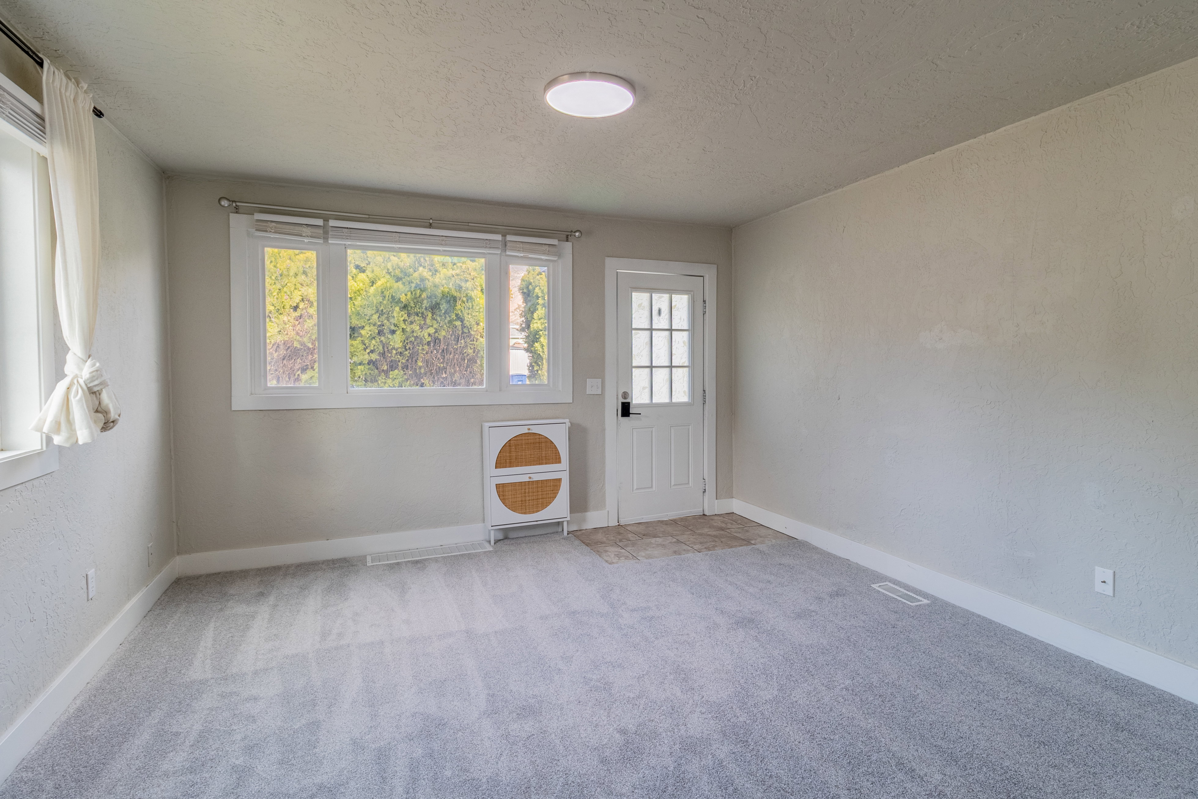 Spacious room featuring light gray carpeting and neutral wall tones