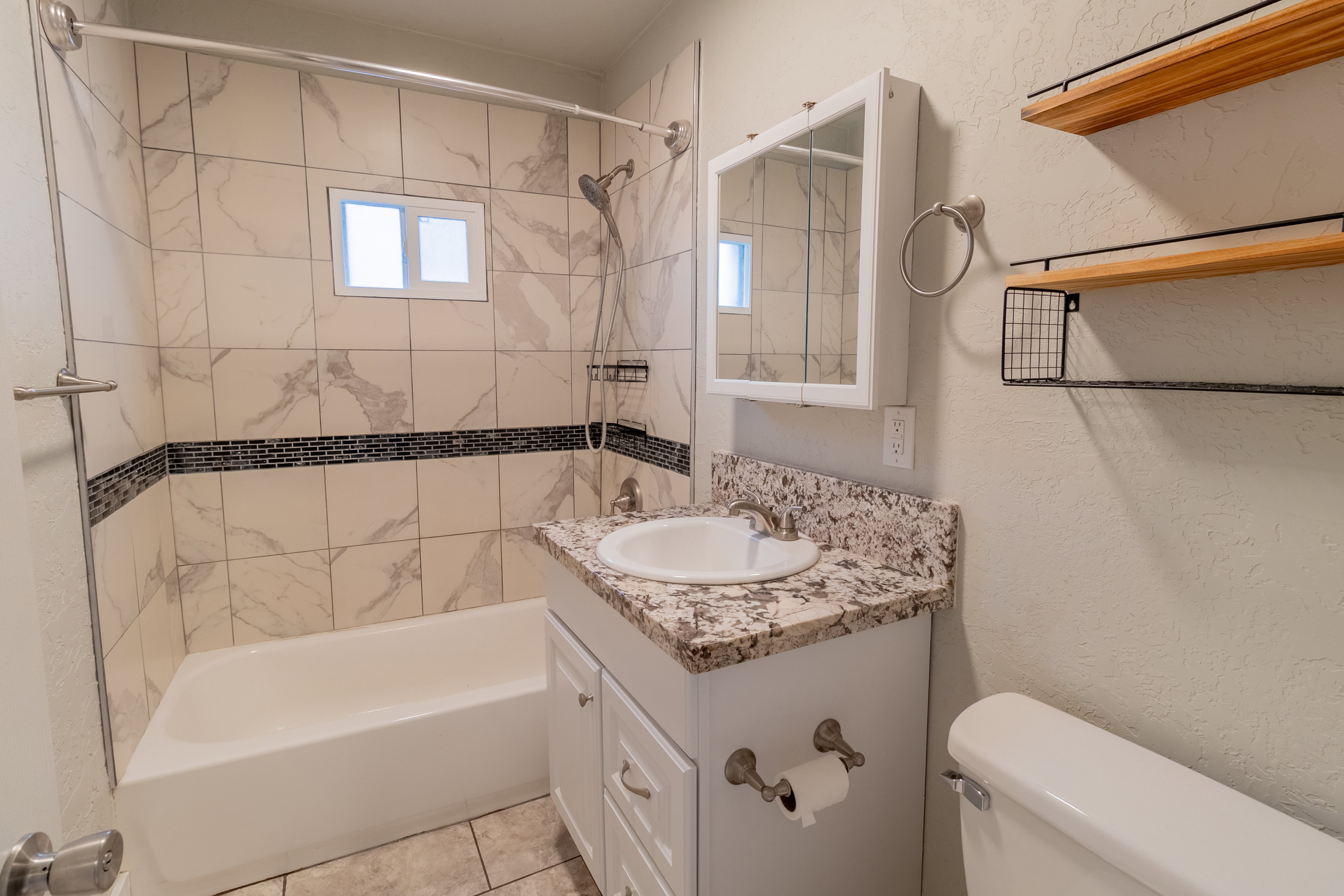 Bathroom featuring a white vanity with a granite-look countertop, a white porcelain sink, and a mirrored medicine cabinet