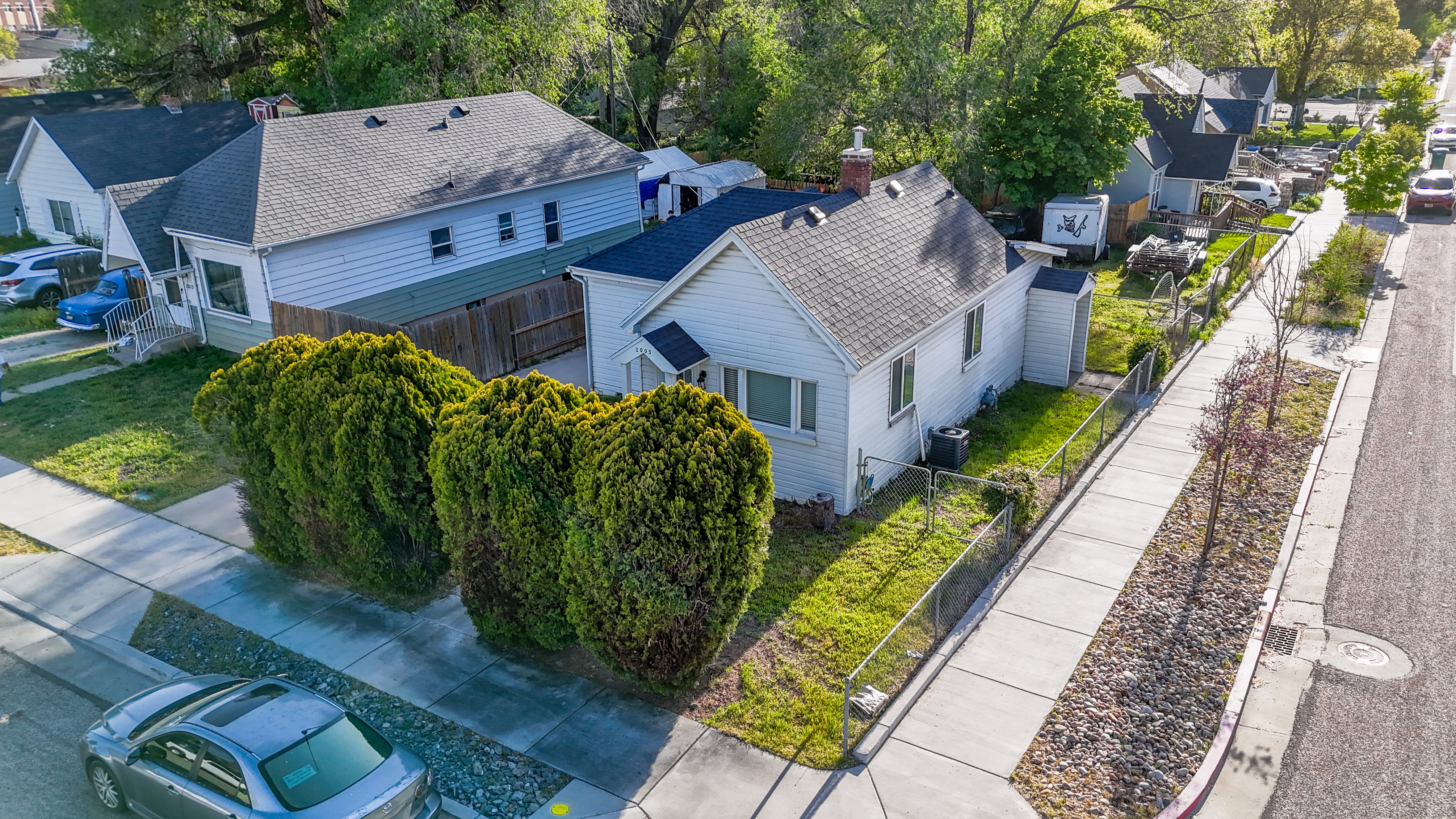 White siding residence featuring a dark shingle roof and a concrete sidewalk