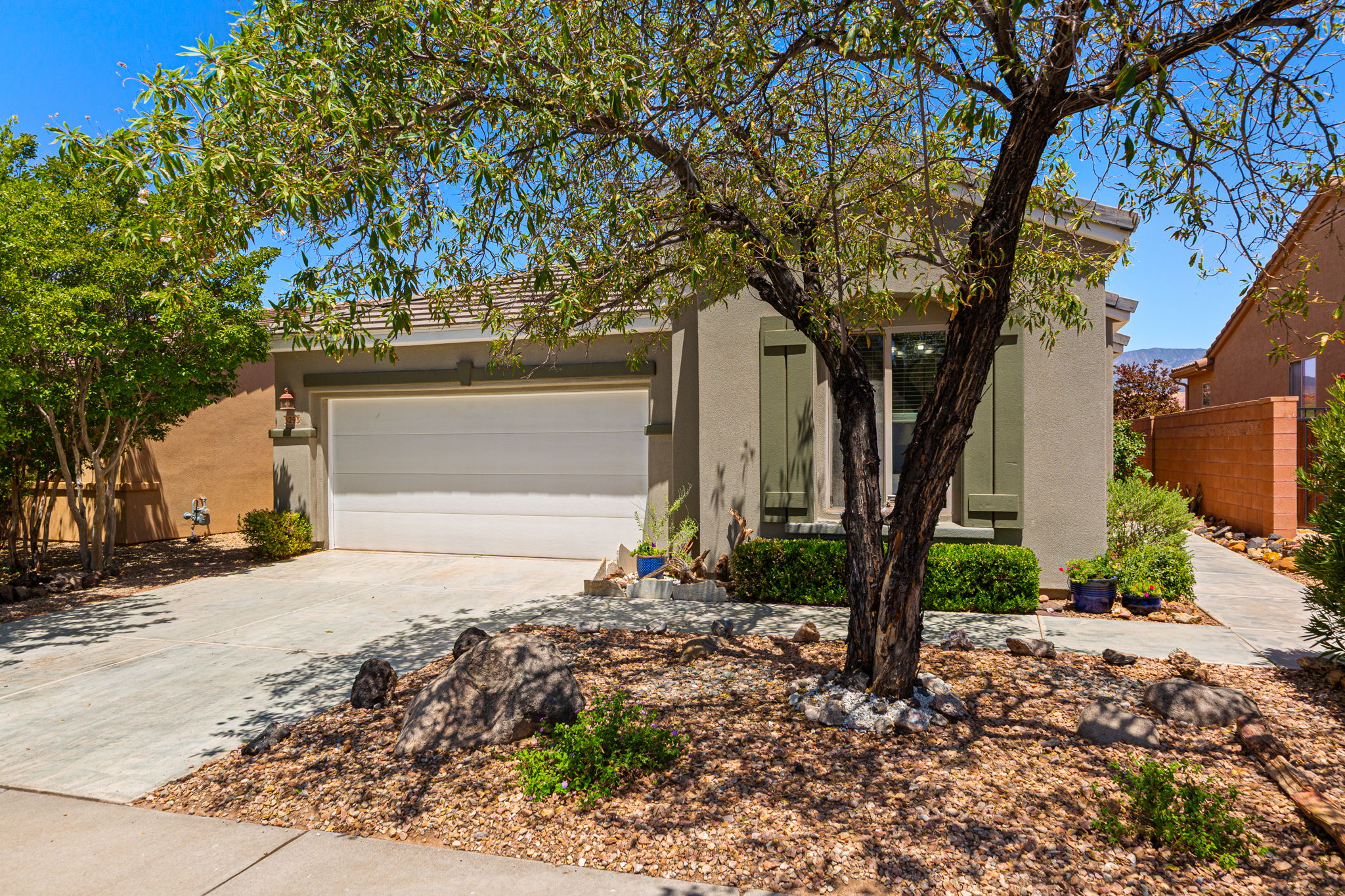 Stucco exterior with a tiled roof, featuring an integrated two-car garage and a concrete driveway