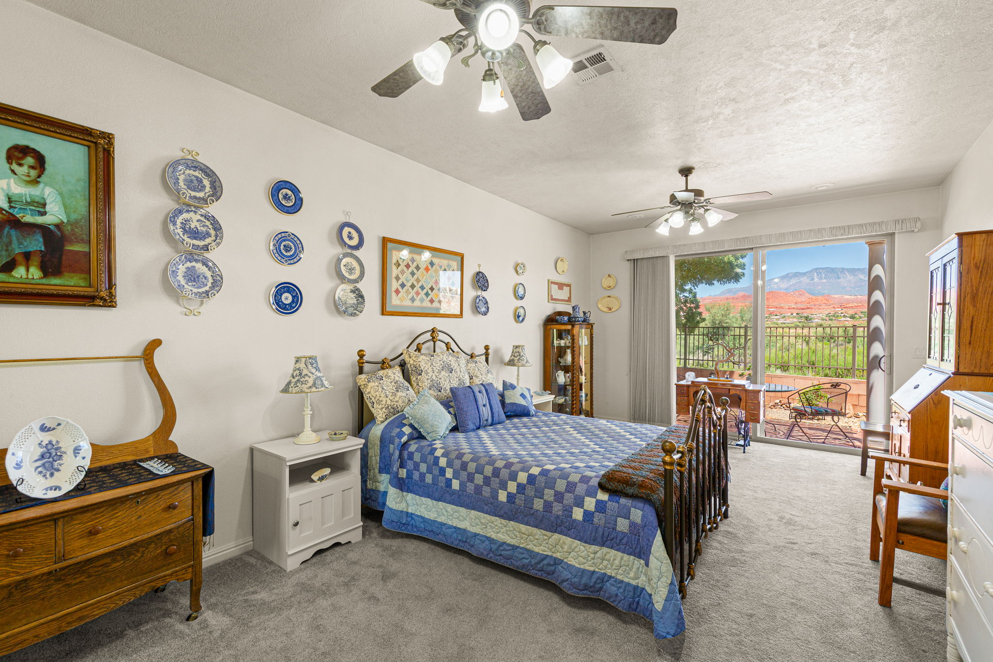 Carpeted room featuring a ceiling fan, sliding glass door, and outdoor patio space with wrought iron railing
