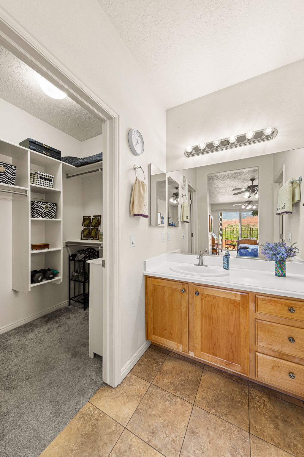 Bathroom vanity with dual sinks, light wood cabinetry, and a full-width mirror