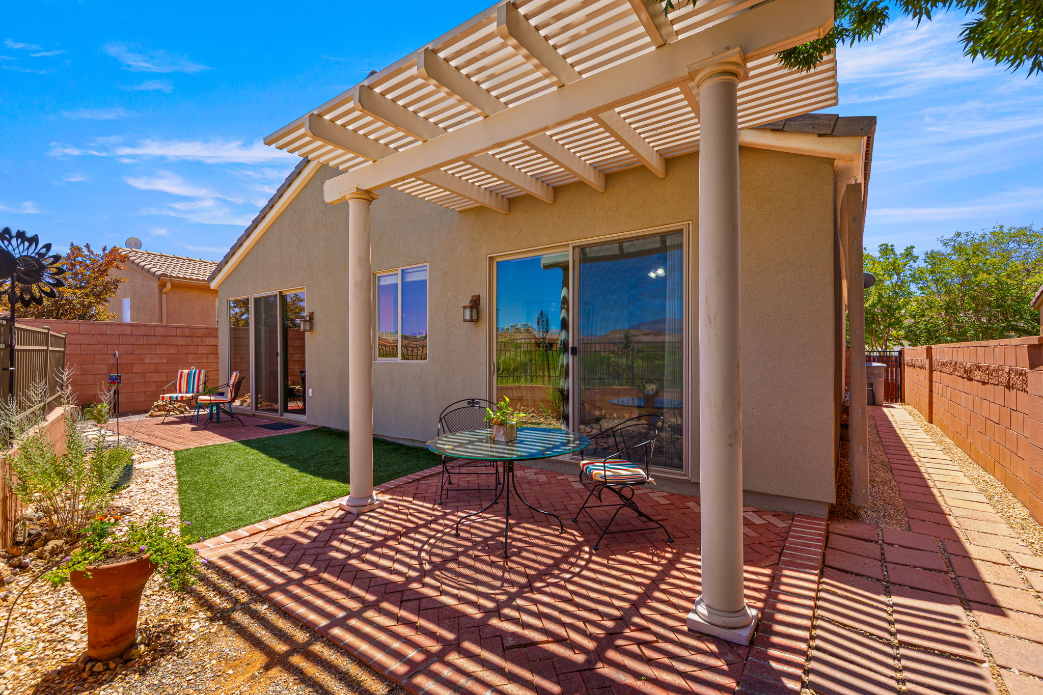 Covered brick patio with a slatted pergola