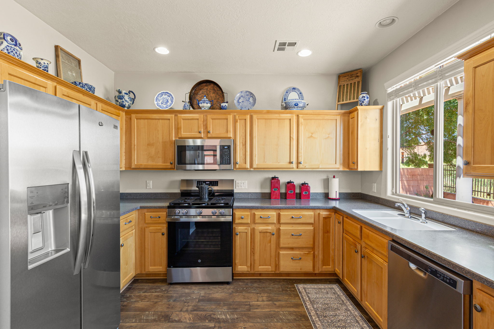 Kitchen featuring wood-finish cabinetry, stainless steel appliances, a double basin sink, and wood-finish flooring