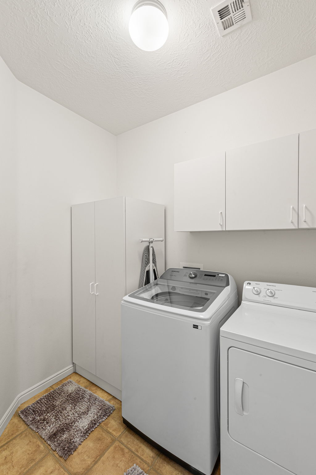 Laundry area with tile flooring, white walls, and built-in white cabinetry providing storage