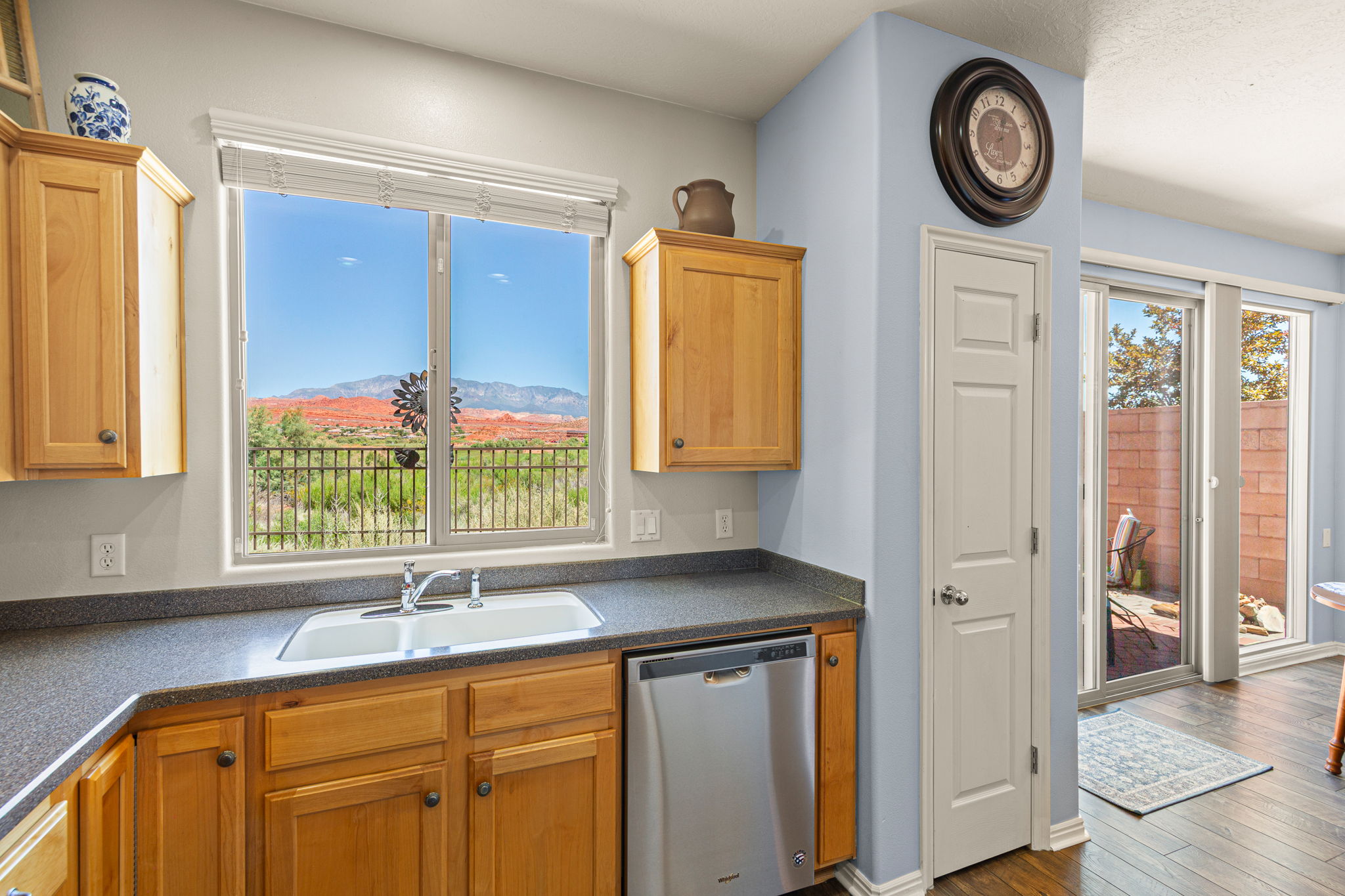 Kitchen featuring wood cabinetry, a double basin sink, and an integrated dishwasher