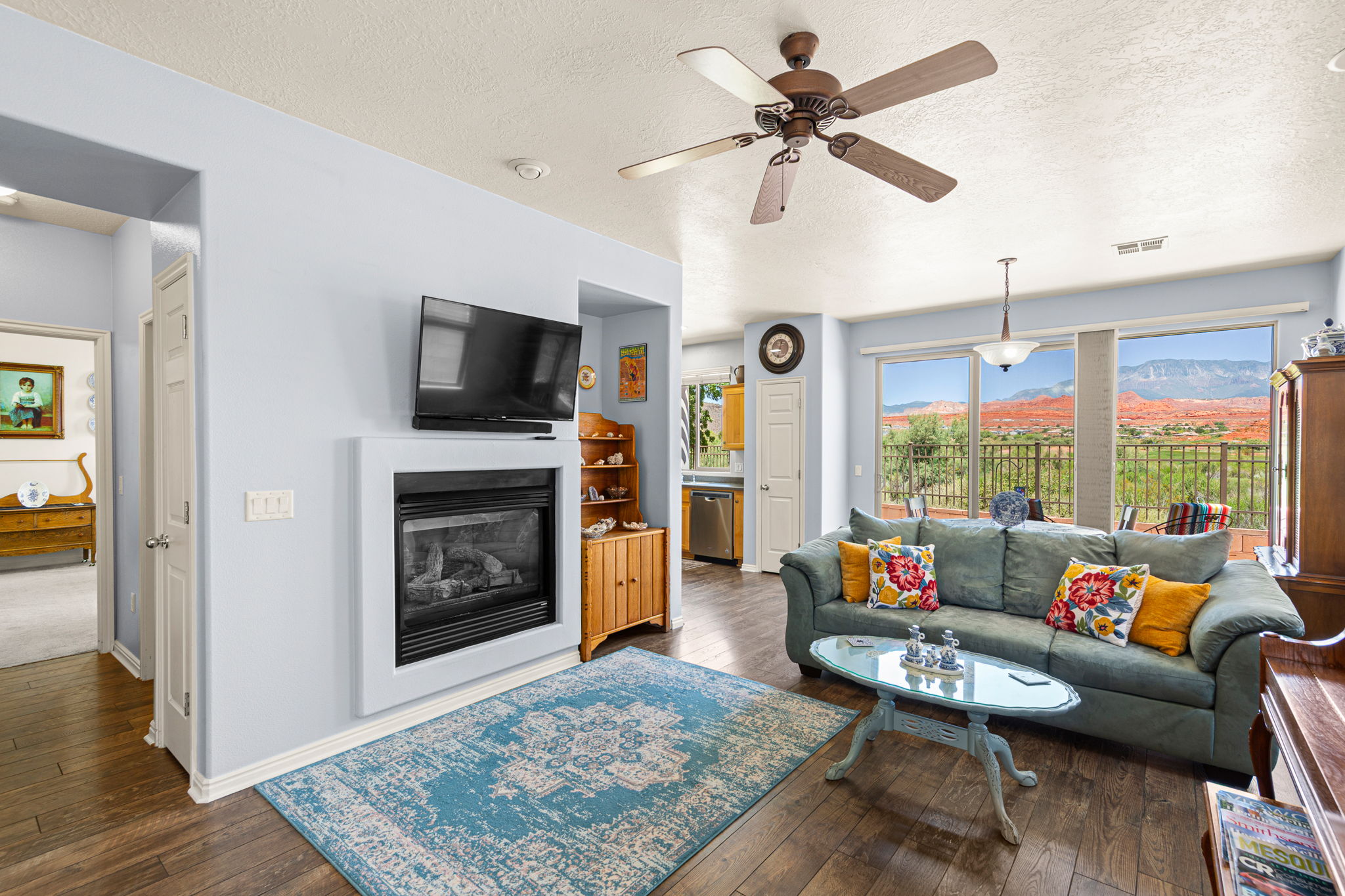 Living area featuring wood-finish flooring, a built-in fireplace, a ceiling fan with integrated lighting, and a large sliding glass door with expansive scenery
