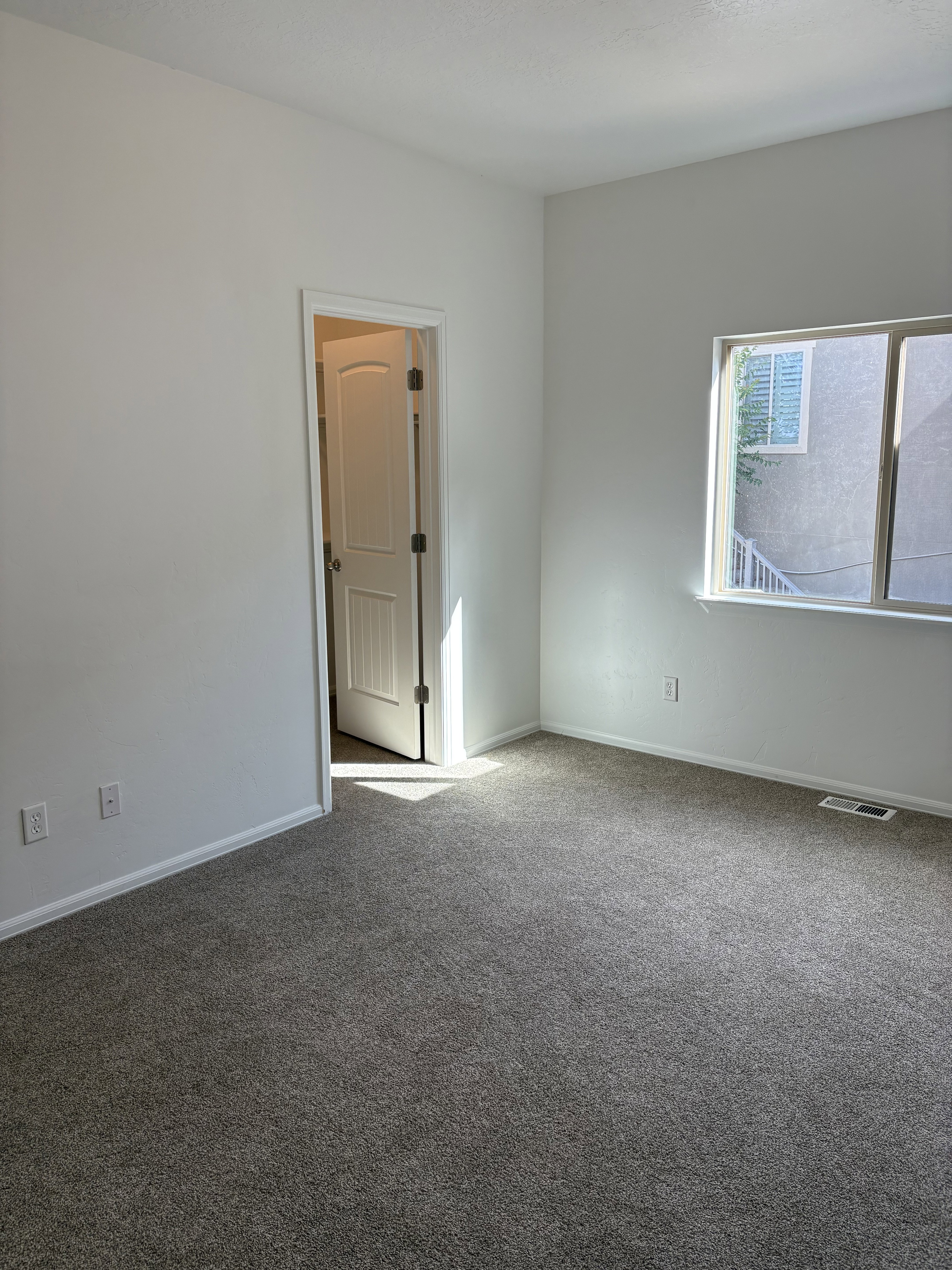 Neutral-toned wall-to-wall carpeting complements the white walls and trim