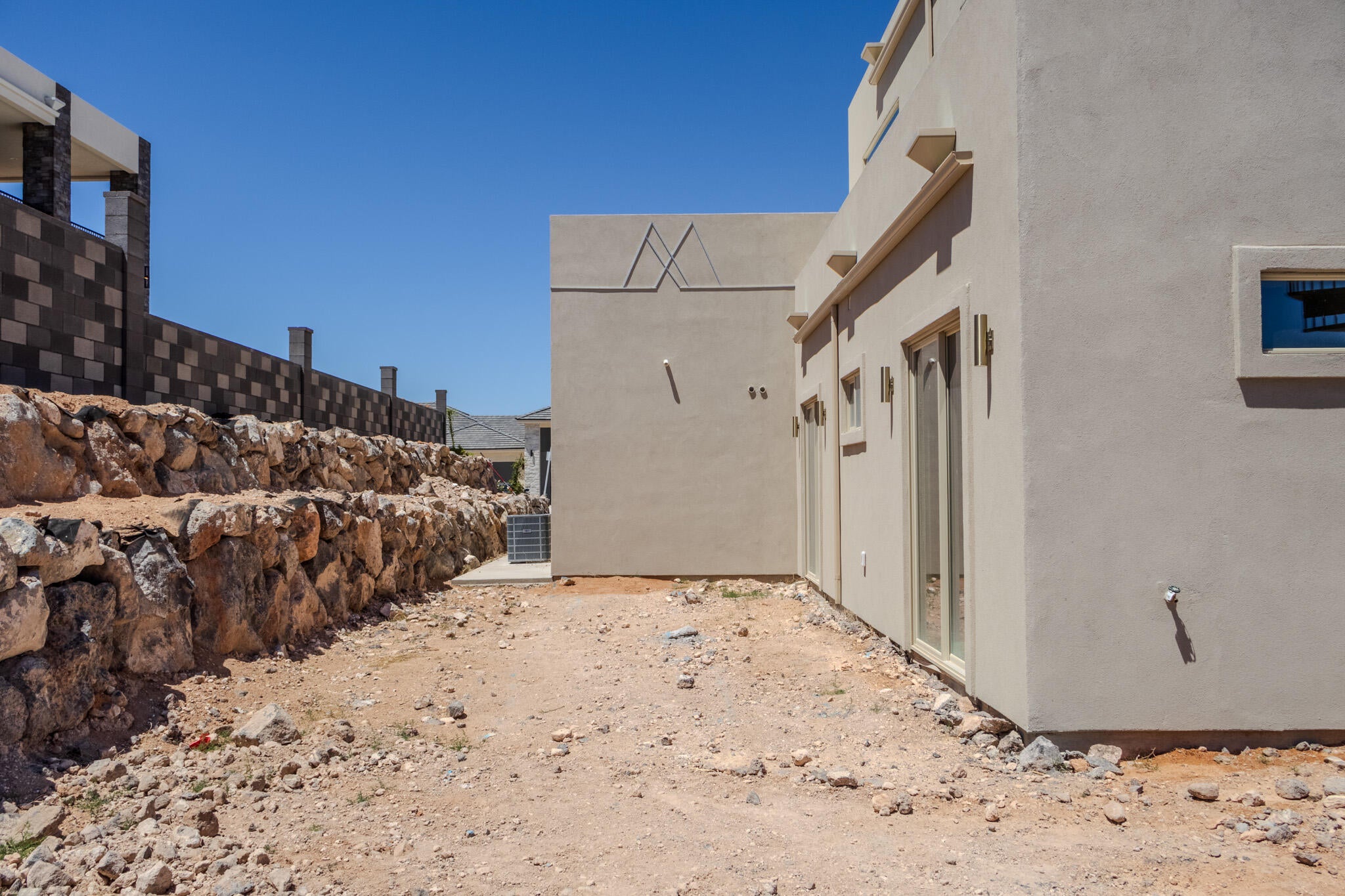 South-facing stucco exterior featuring multiple sliding glass doors and a square window