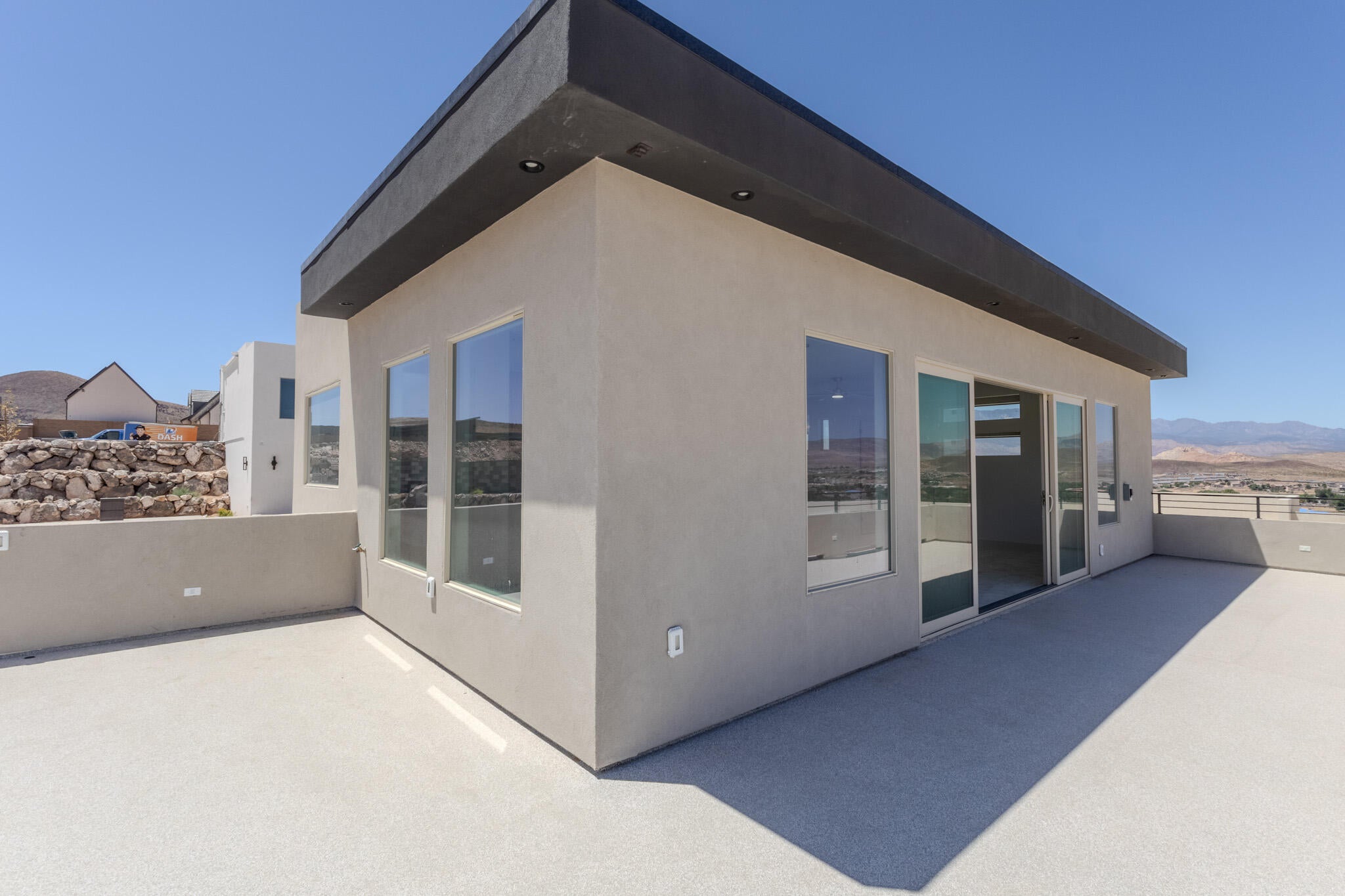 Rooftop deck featuring a contemporary stucco exterior, flat roofline, recessed lighting, expansive windows, and a sliding glass door