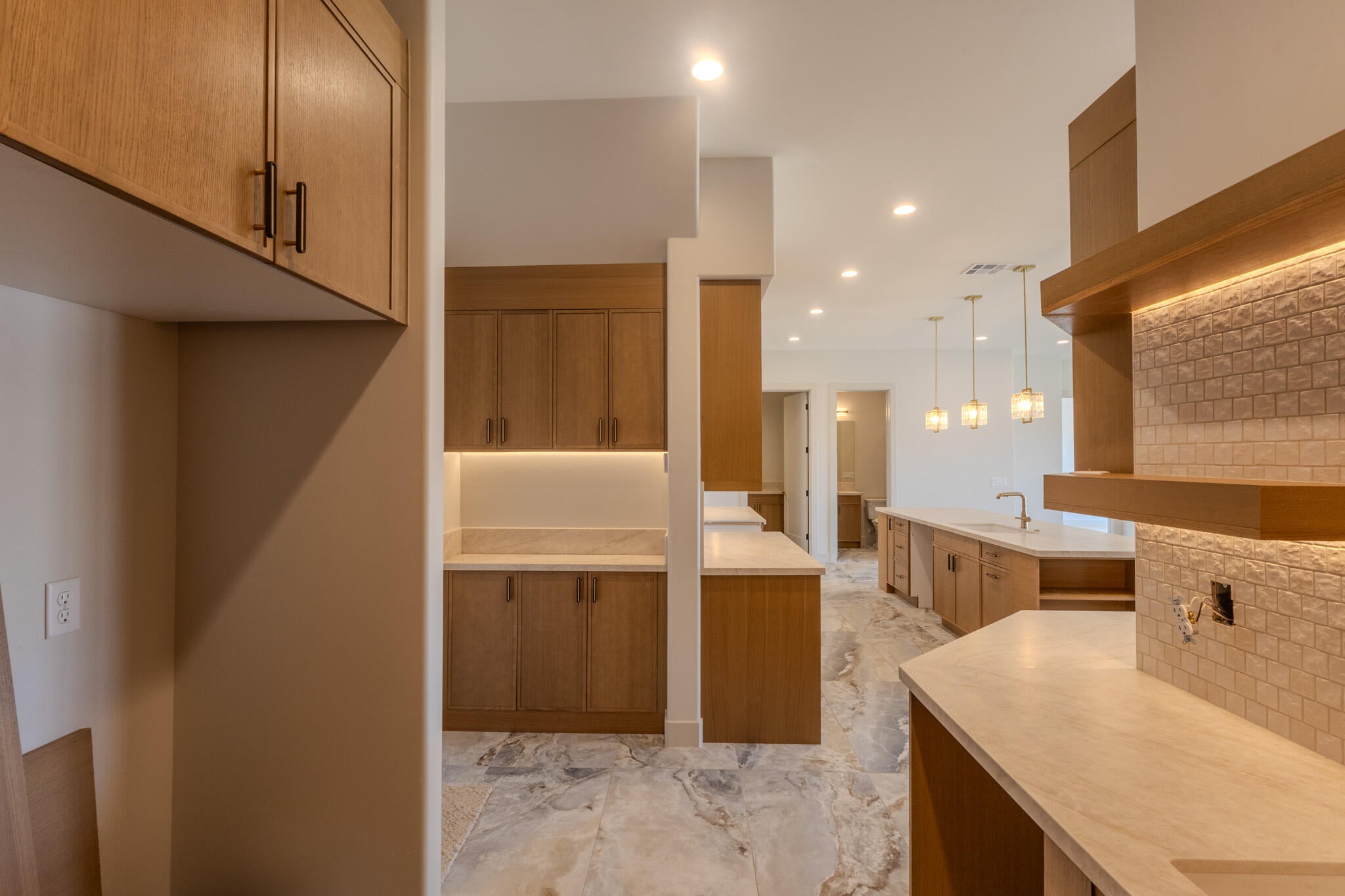 Contemporary kitchen featuring light wood cabinetry, stone countertops, and recessed lighting