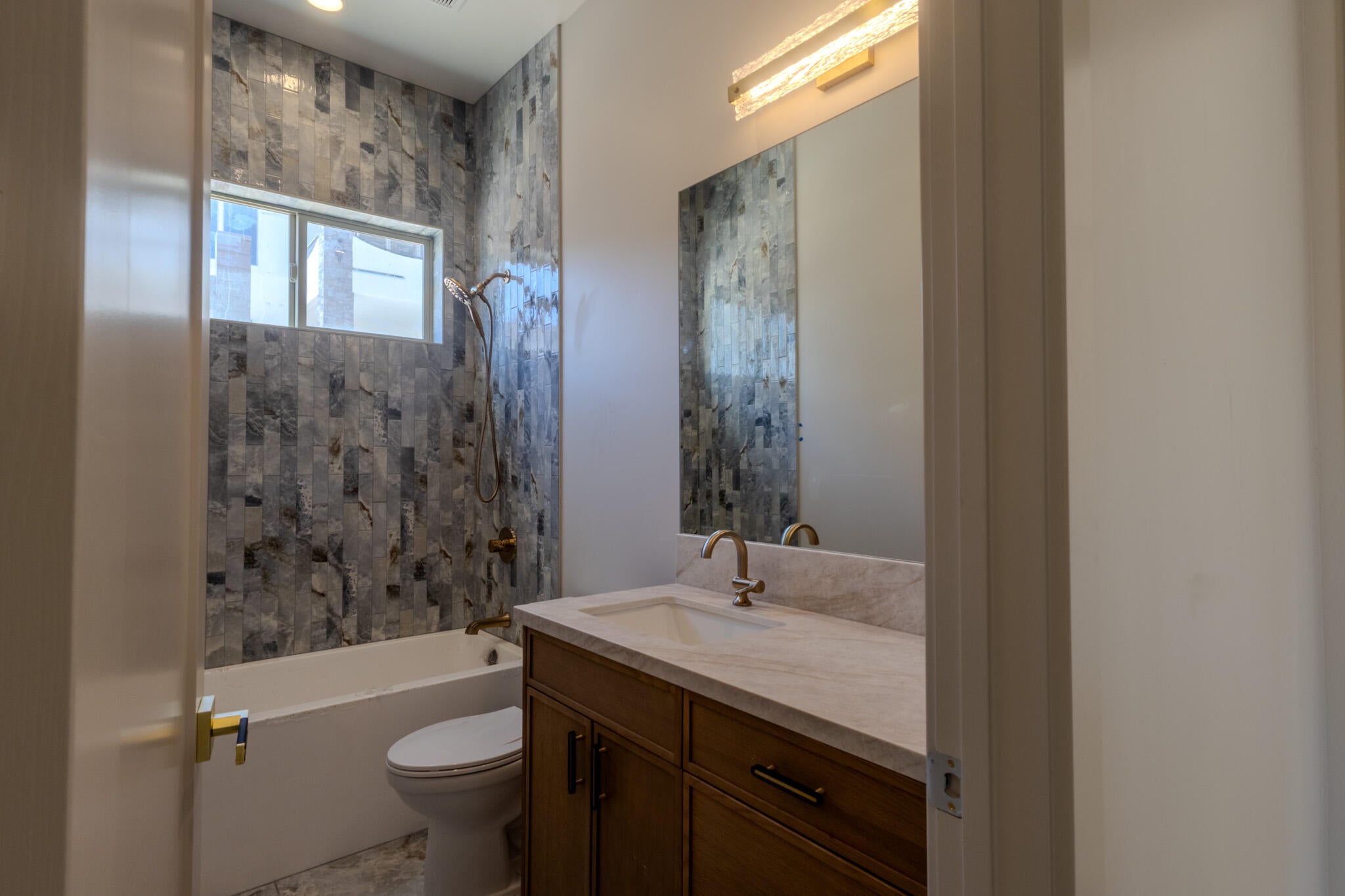 Bathroom featuring a tiled shower surround, integrated bathtub, and bronze-finish fixtures