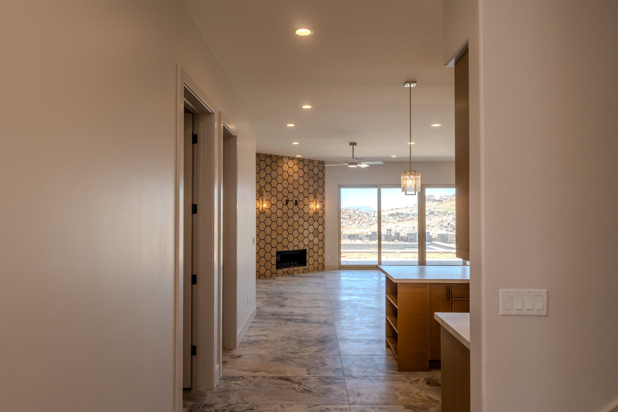 Open concept living area featuring expansive sliding glass doors, a geometric accent wall with an integrated fireplace, and recessed lighting