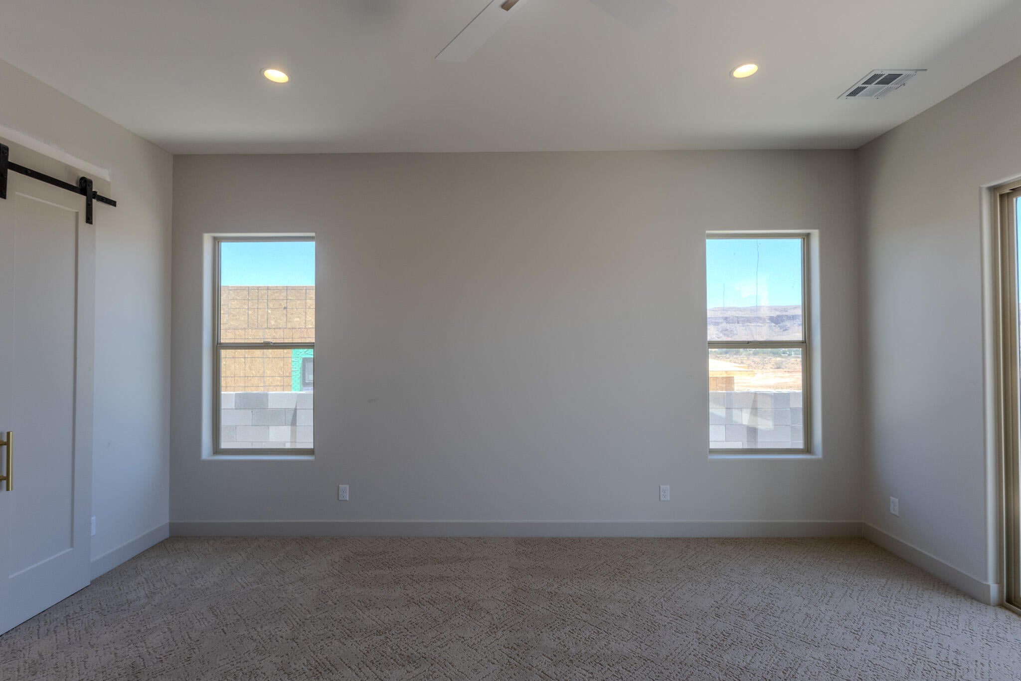 Spacious room with plush carpeting, recessed lighting, and modern windows offering distant mountain scenery