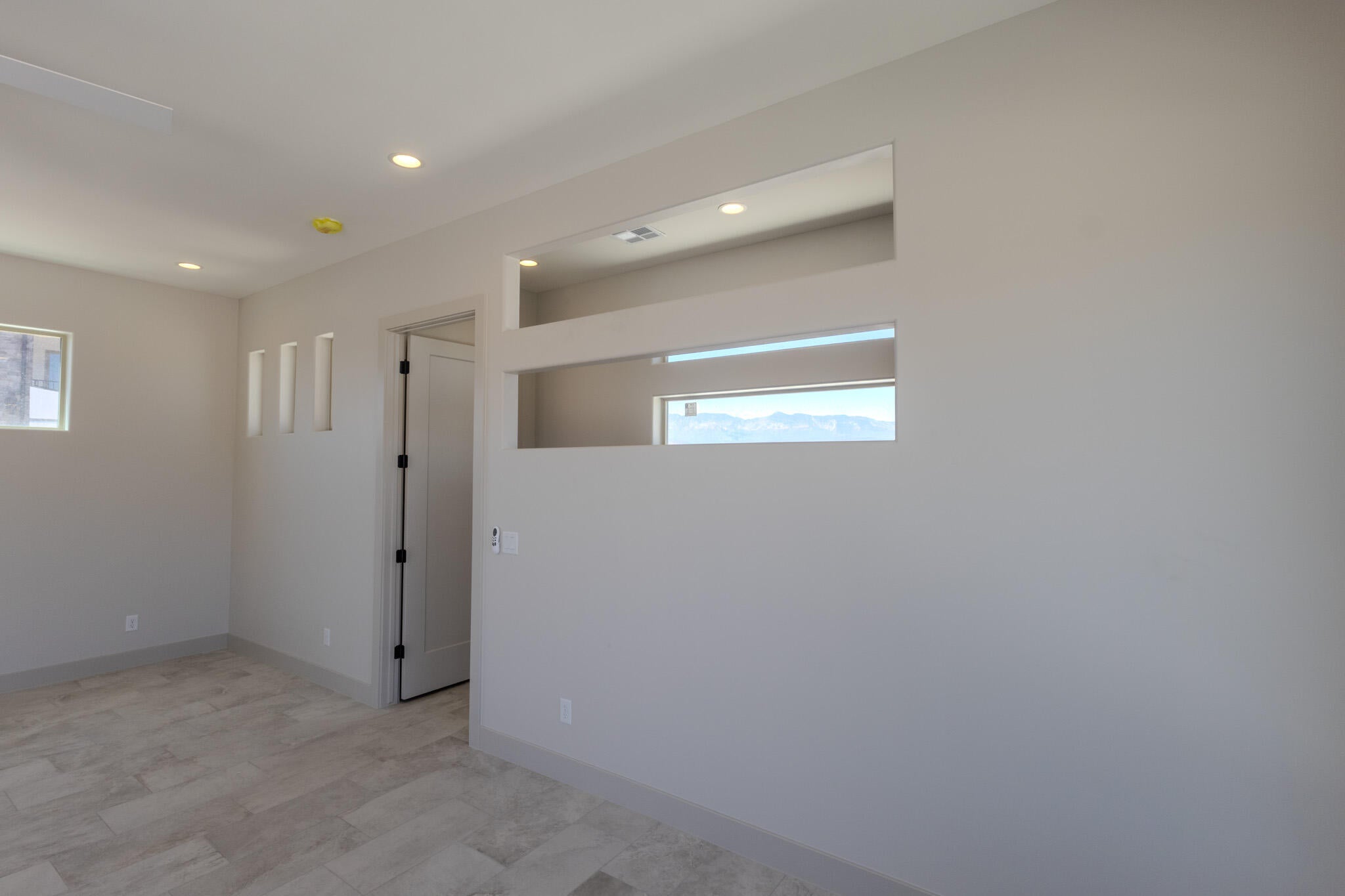 Neutral-toned interior featuring wood-finish flooring, recessed lighting, and a modern interior door with black hardware