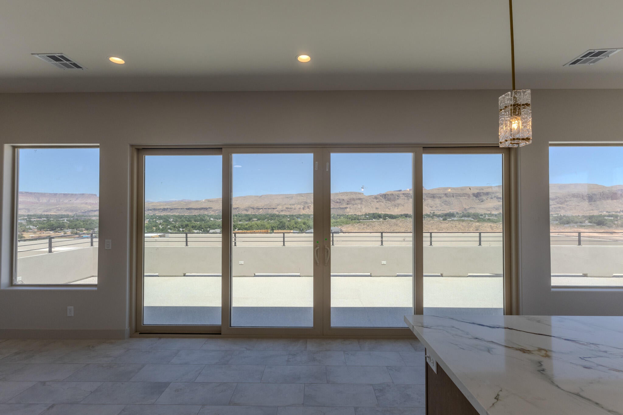 Expansive glass sliding doors open to a spacious outdoor terrace with a metal railing