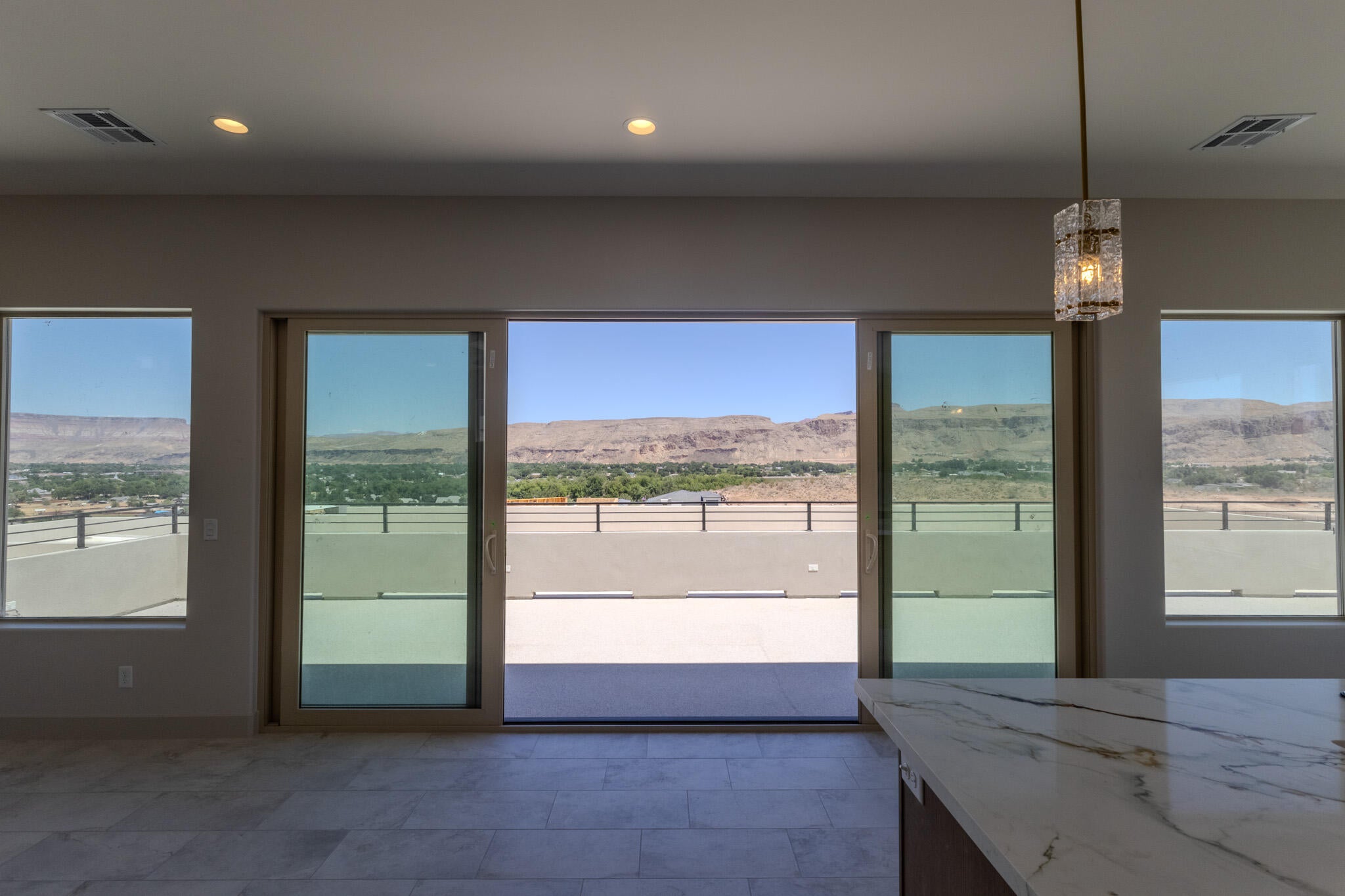 Expansive sliding glass doors open to a spacious balcony, offering panoramic desert and cityscape scenery