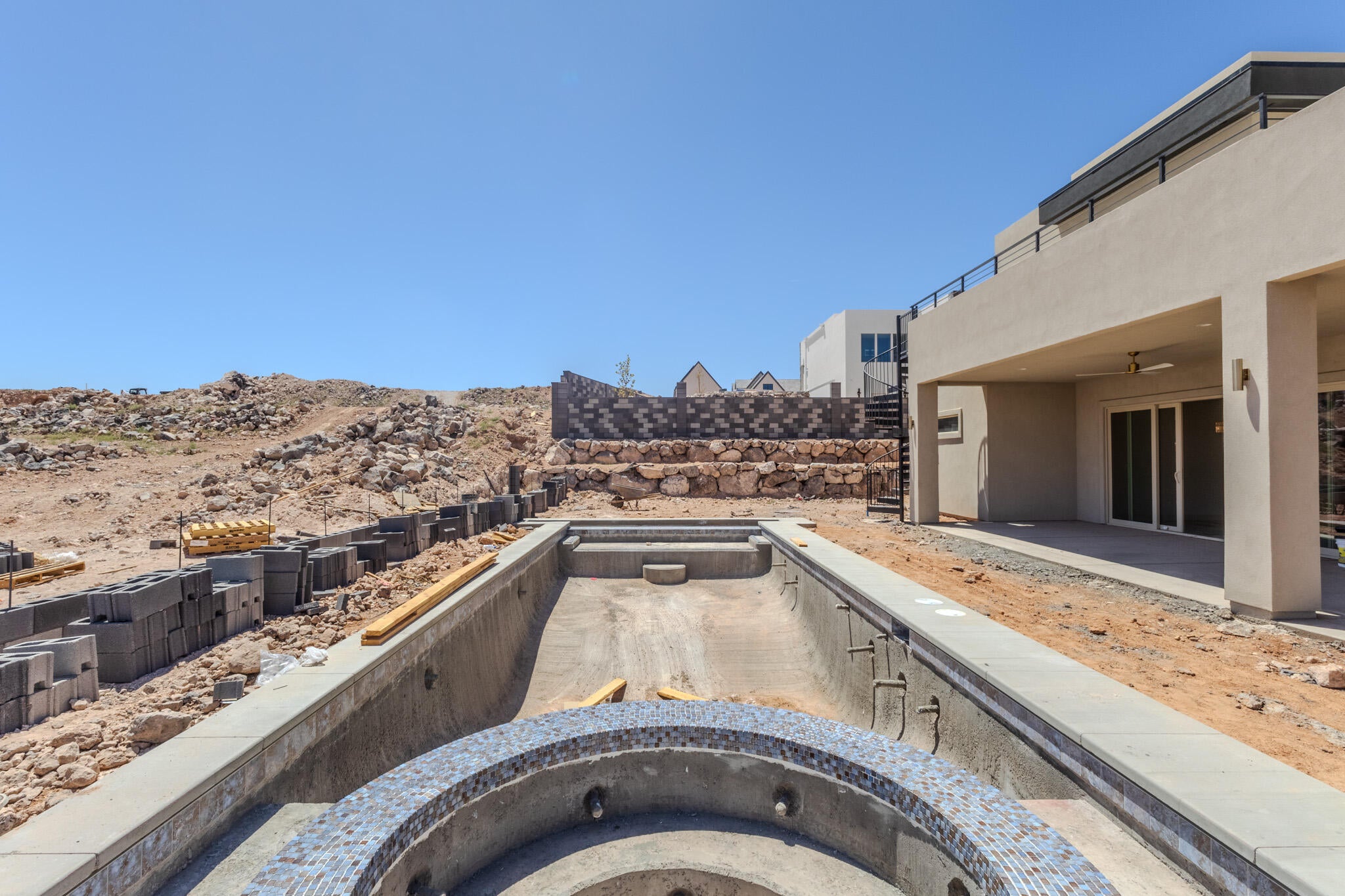 Unfinished pool and spa area with blue mosaic tiling and an integrated concrete perimeter